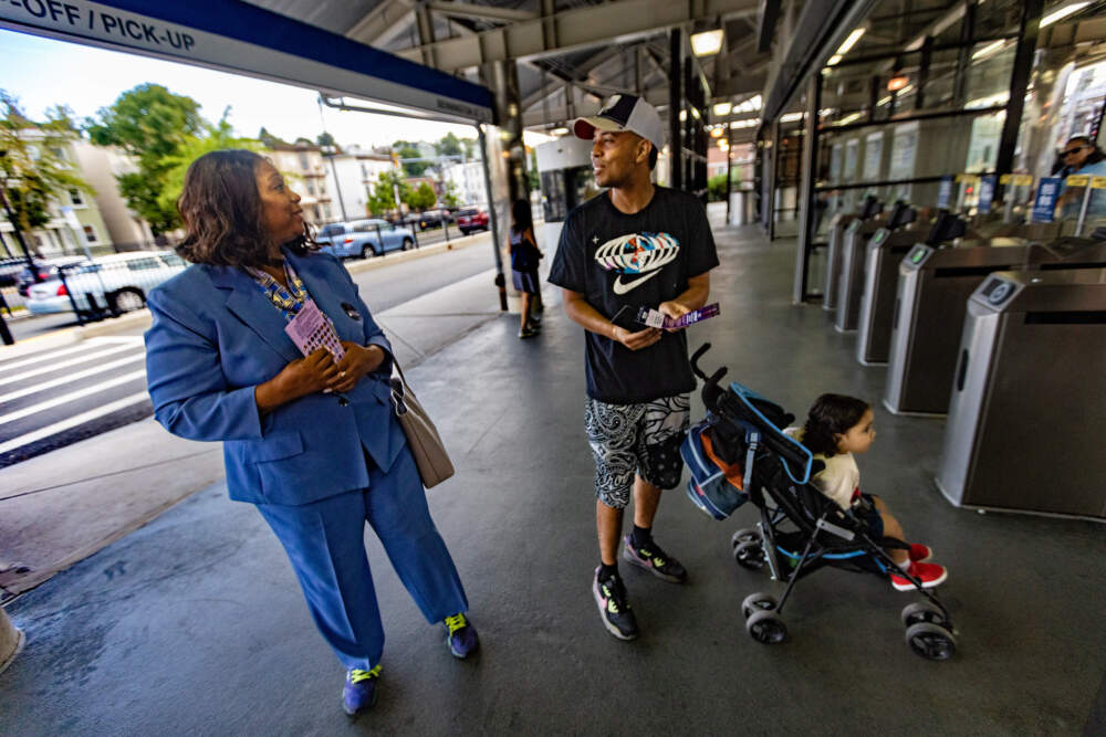 Allison Cartwright speaks with a voter while campaigning outside the Orient Heights MBTA station in East Boston. (Jesse Costa/WBUR)
