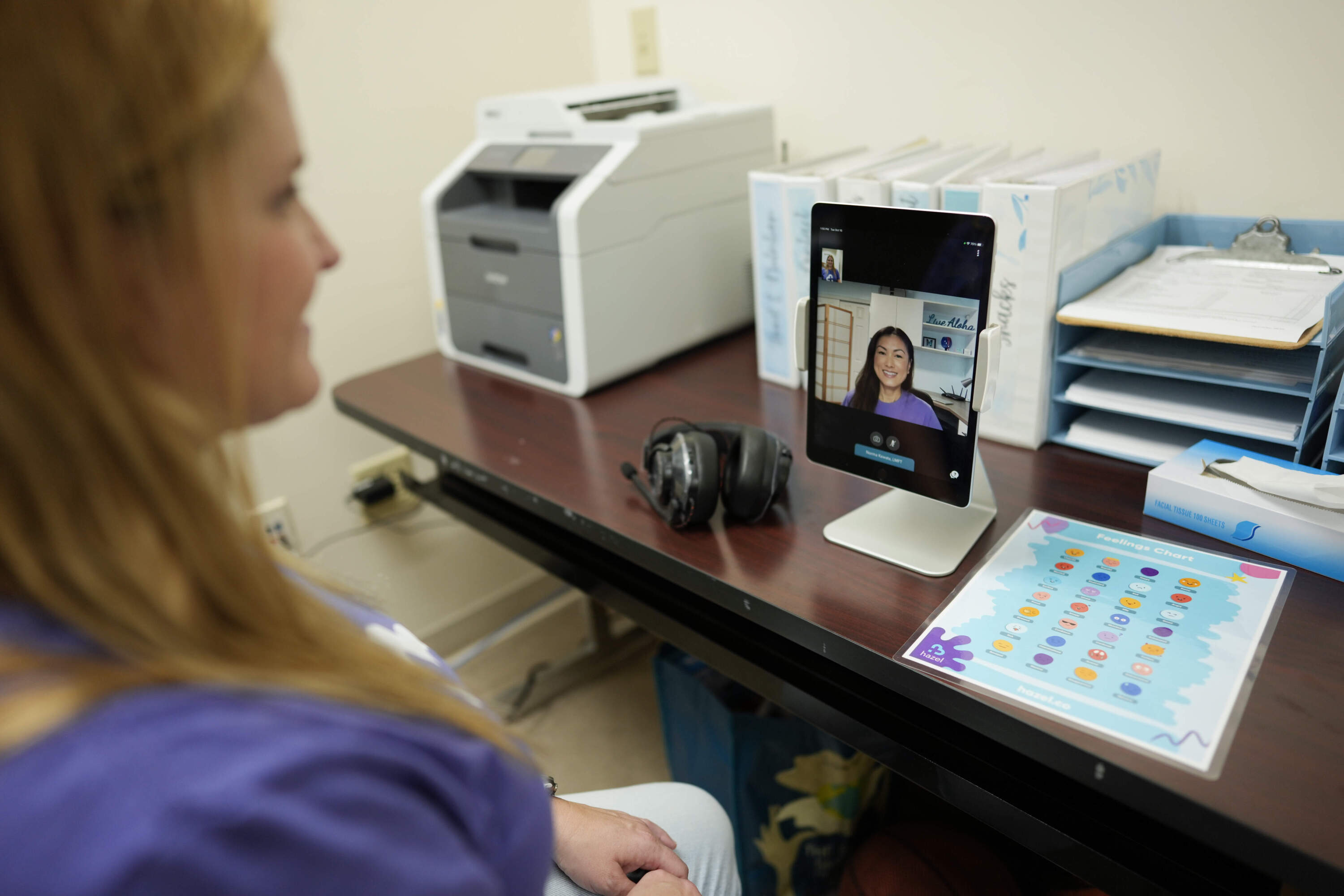 Therapist Norma Kawatta, seen on screen, talks to Paris Carroll, VP of mental health clinical services for Hazel Health, as the pair demonstrate how the company's telehealth therapy service works. (Rebecca Blackwell/AP)