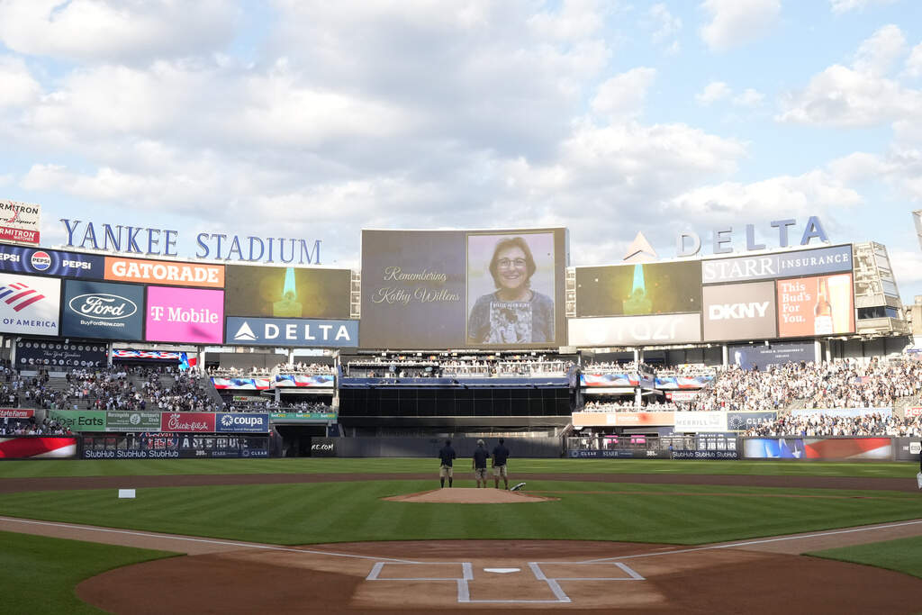 Players and fans stand at Yankee Stadium during a moment of silence for Kathy Willens before of a baseball game on Friday, July 19, 2024, in New York. Willens, a pathbreaking photojournalist who helped cement women's place behind the lens everywhere from the Super Bowl to war-torn Somalia during her nearly 45-year career at The Associated Press, died on July 16. She was 74. (Frank Franklin II/AP)