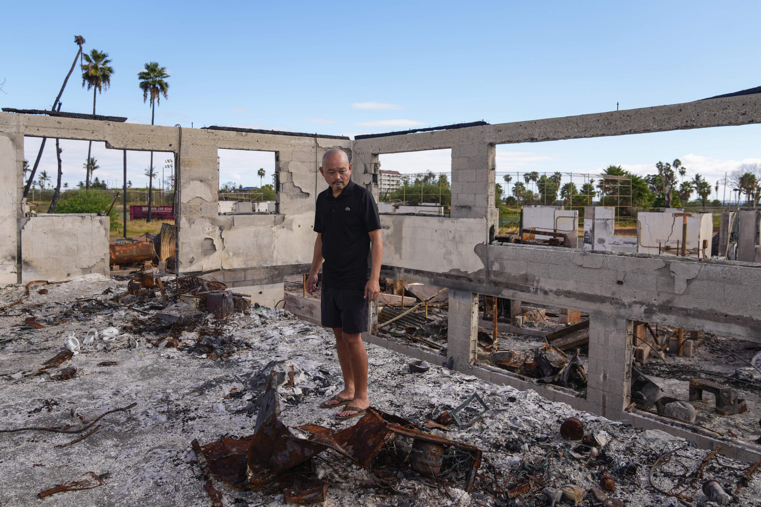 The Rev. Ai Hironaka looks down at his former temple and residence, the Lahaina Hongwanji Mission, destroyed in the 2023 wildfires. (Lindsey Wasson/AP)