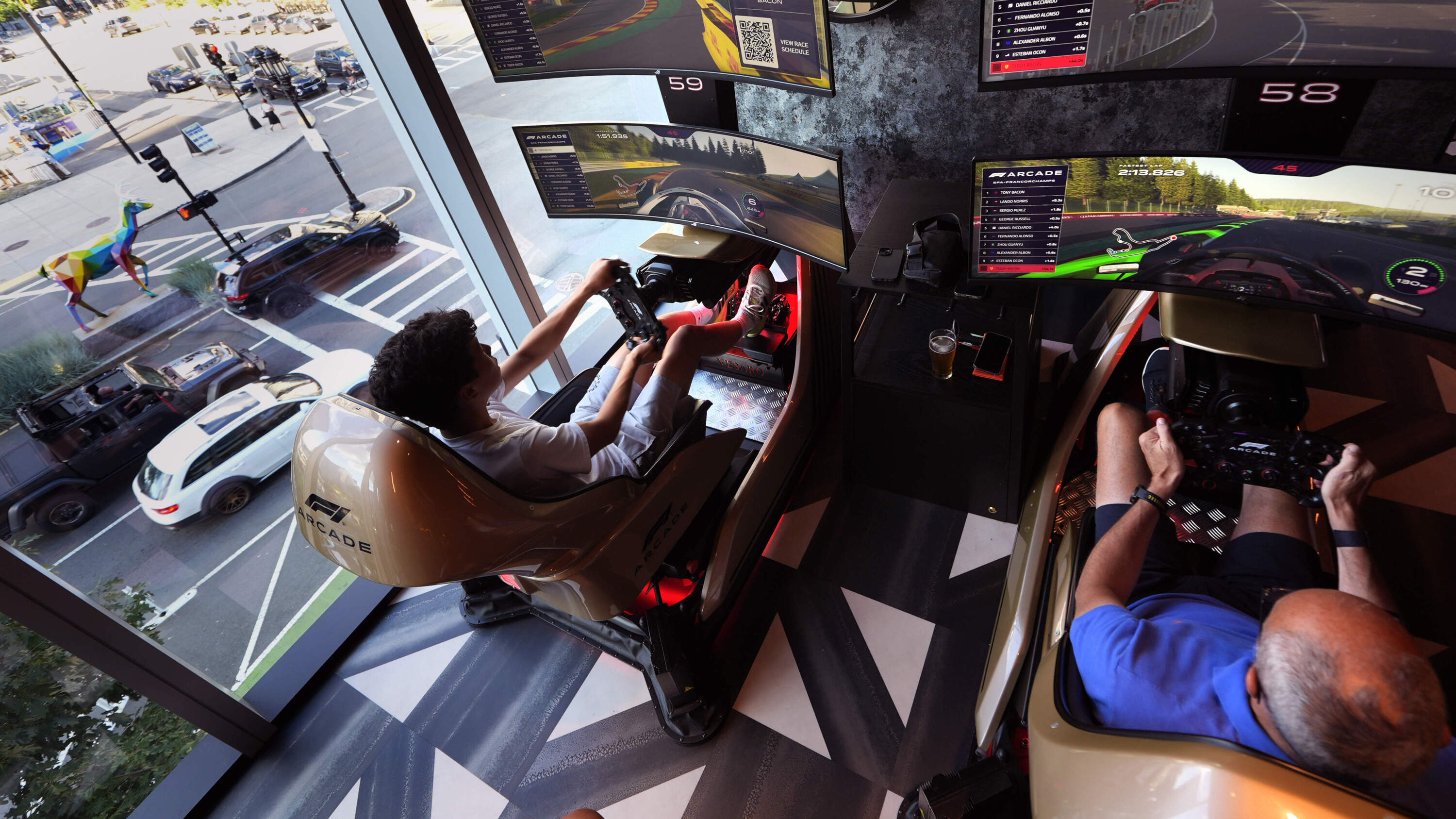 With traffic seen passing through a nearby window, Teddy Bacon, of England, races his father Tony at the F1 Boston Arcade, Monday, July 8, 2024, in Boston. (Charles Krupa/AP)