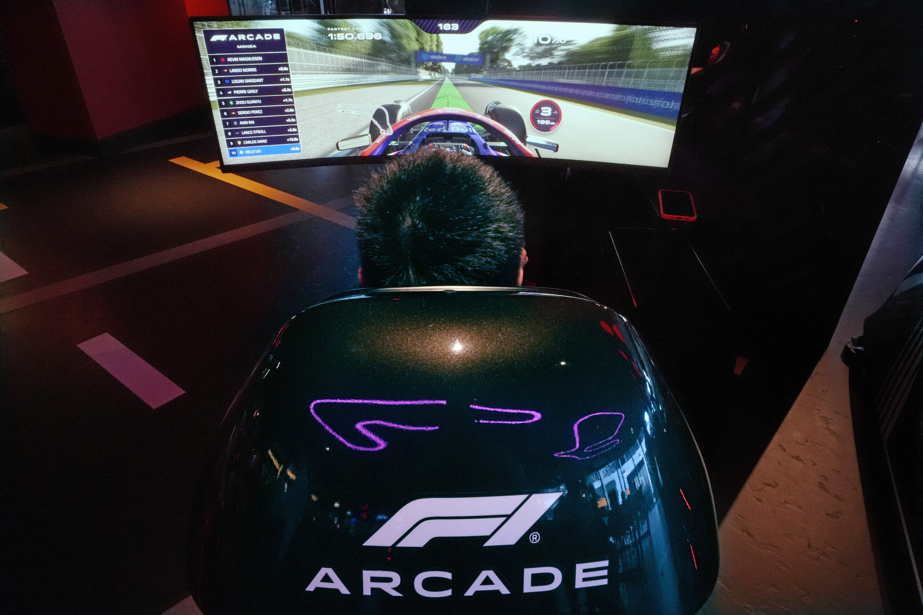 A video game driver races on a simulated track at the F1 Boston Arcade. (Charles Krupa/AP)