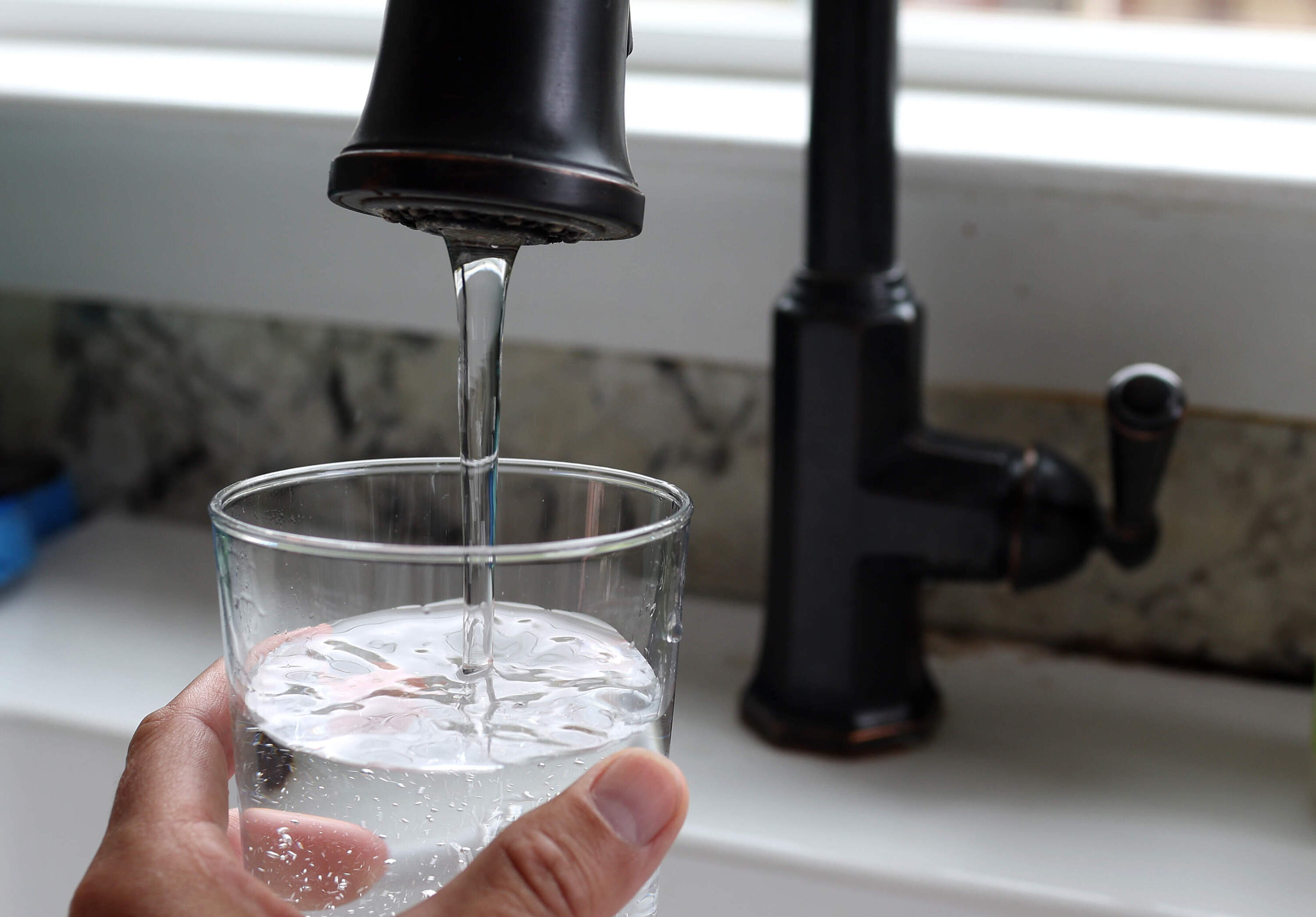 In this photo illustration, water from a tap fills a glass. (Justin Sullivan/Getty Images)