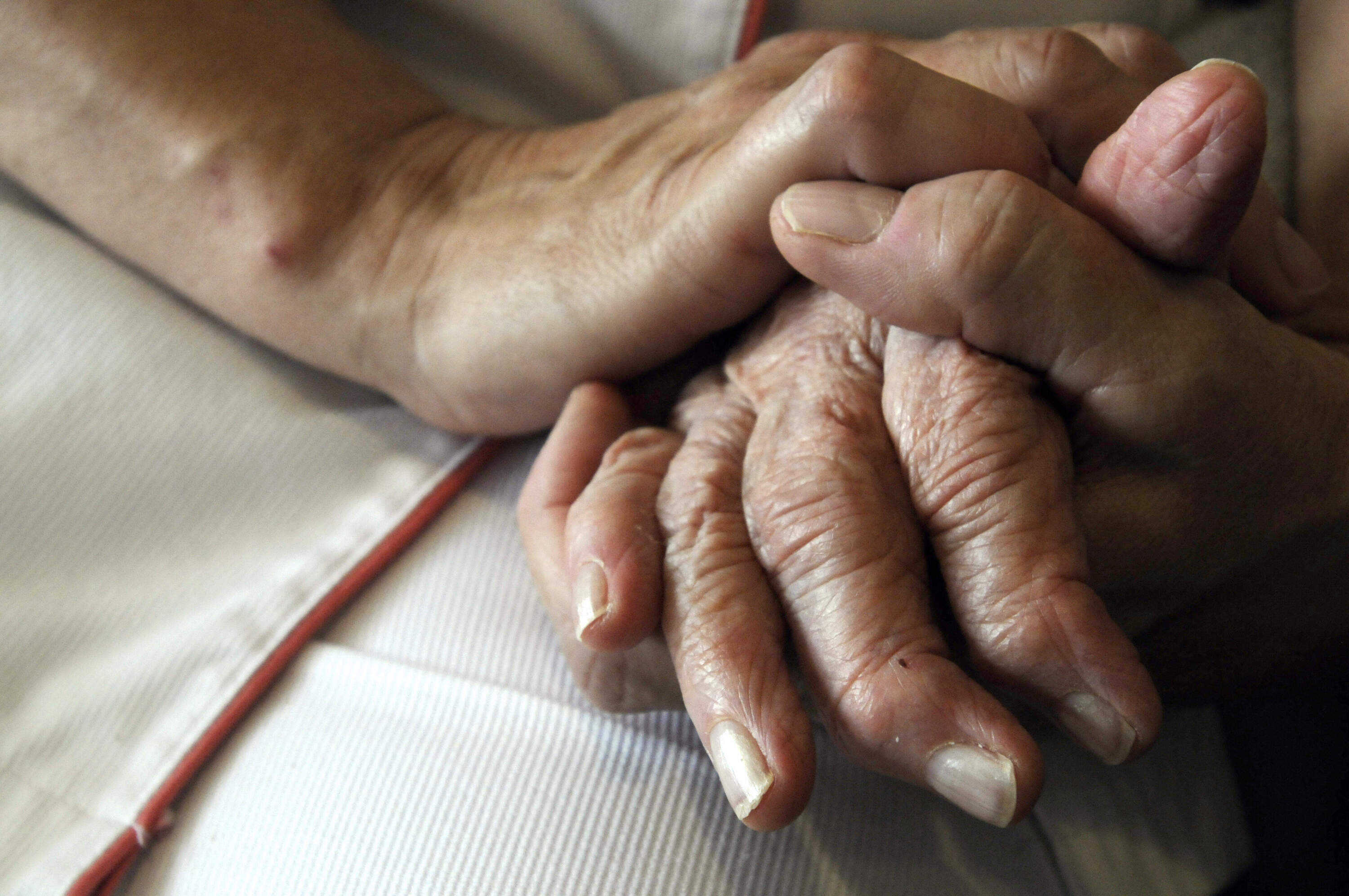 A nurse holds the hands of a person suffering from Alzheimer's disease. (Sebastien Bozon/AFP via Getty Images)