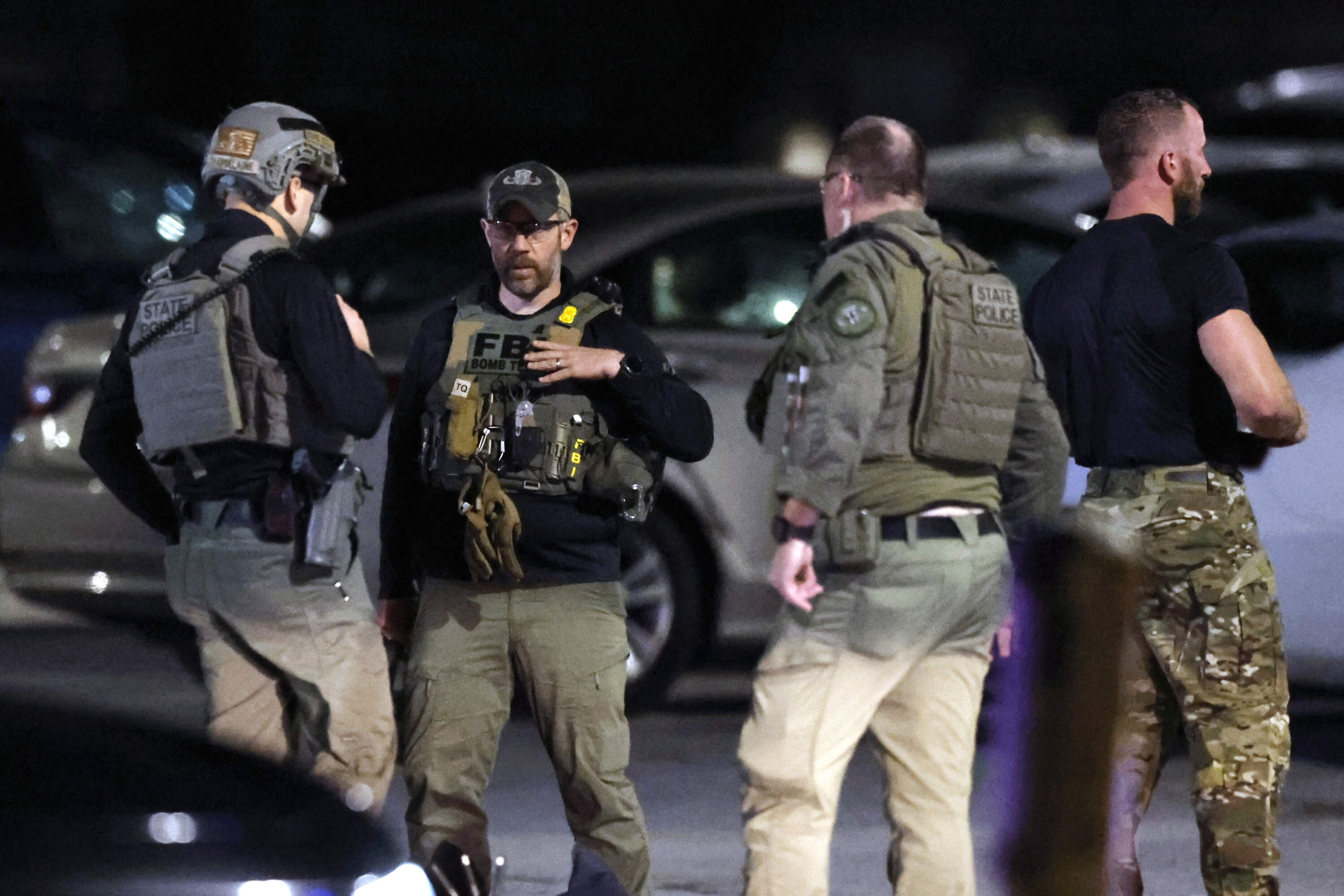 State police and an FBI bomb technician stand at a staging area in the parking lot of New Hampshire Hospital Friday, Nov. 17, 2023, in Concord, N.H. (Michael Dwyer/AP)
