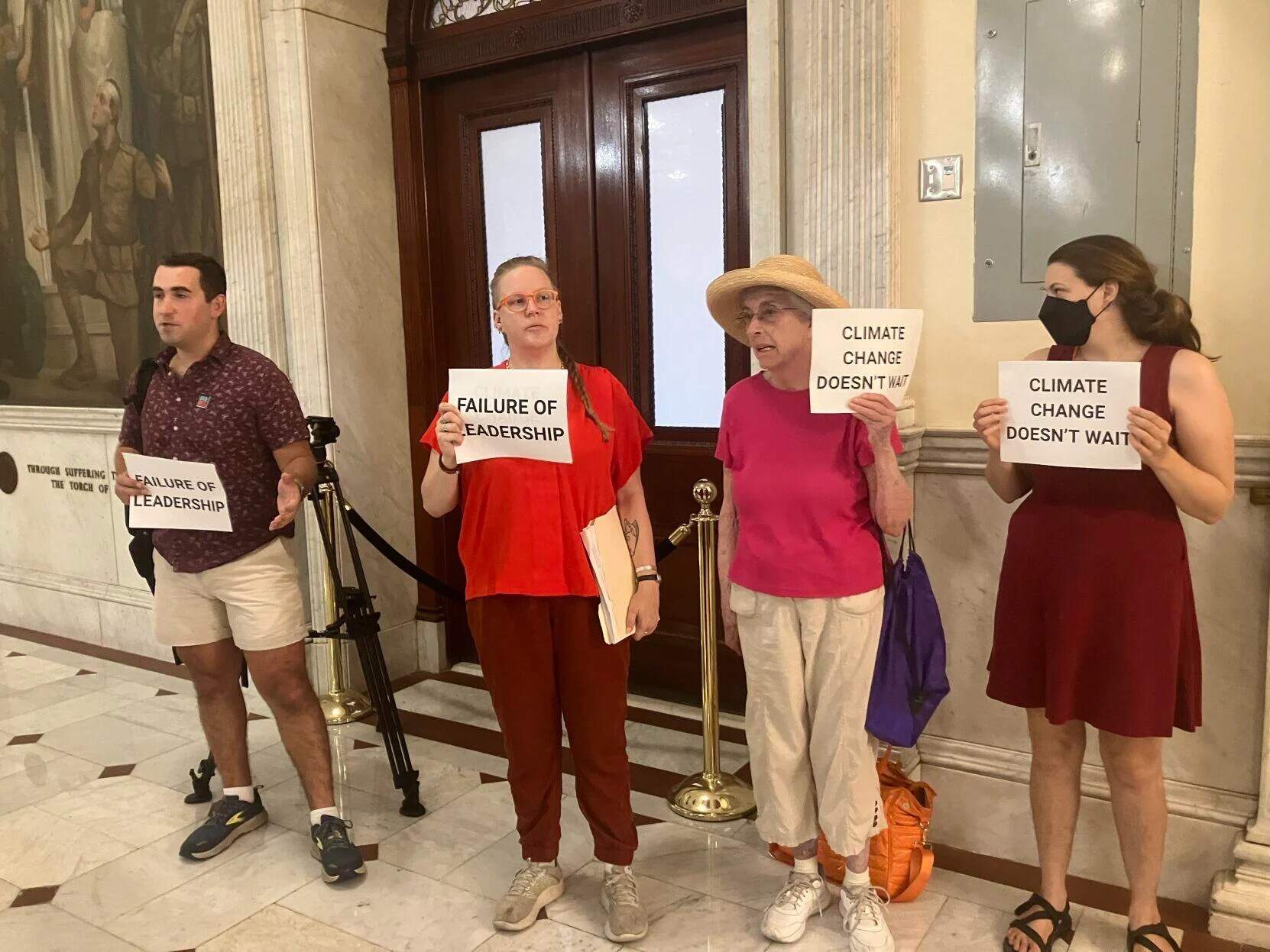 Climate protesters held up signs outside the Senate chamber as the branch adjourned on Thursday, Aug. 1, 2024. (Alison Kuznitz/SHNS)