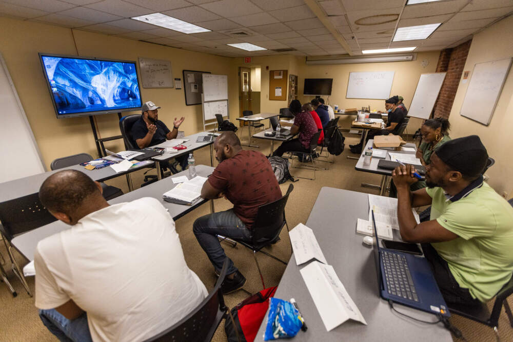 Instructor Carlos Antunas reviews information the students have been studying in their course book. (Jesse Costa/WBUR)