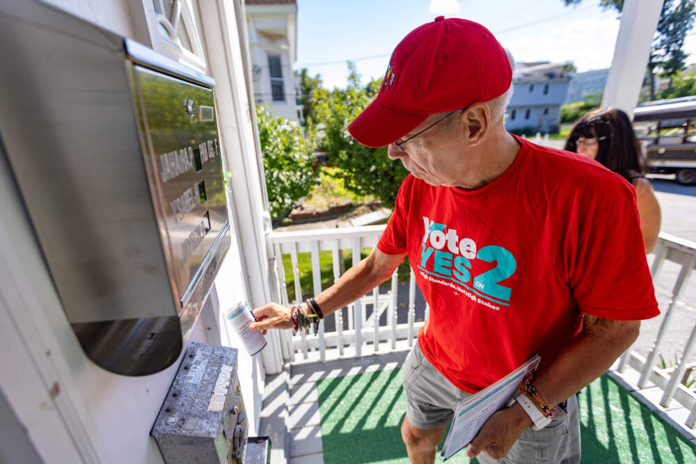 Retired Andover High School teacher Tom Meyers leaves literature in the door of a home on Jamaica Street while canvassing in Lawrence in support of Question 2. (Jesse Costa/WBUR)