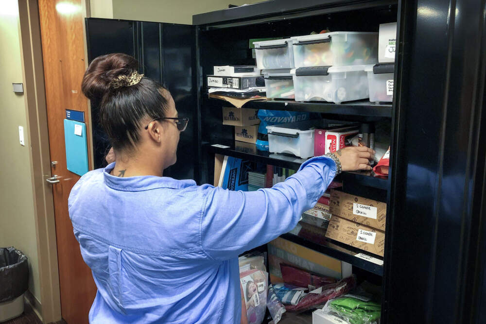 Nurse Rosali Santiago goes into the cabinet of prizes at Brockton Neighborhood Health Center. (Martha Bebinger/WBUR)