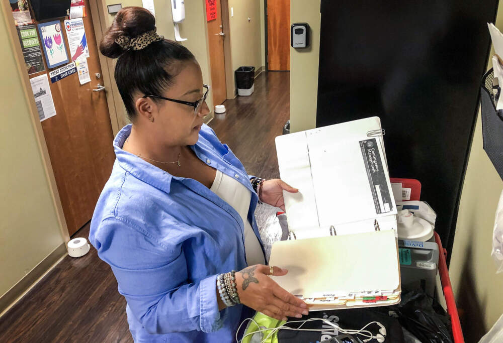 Rosali Santiago, a nurse at Brockton Neighborhood Health Center, tracks prizes awarded each contingency management patient to make sure they don't exceed a federal cap of $75 per patient per year. (Martha Bebinger/WBUR)