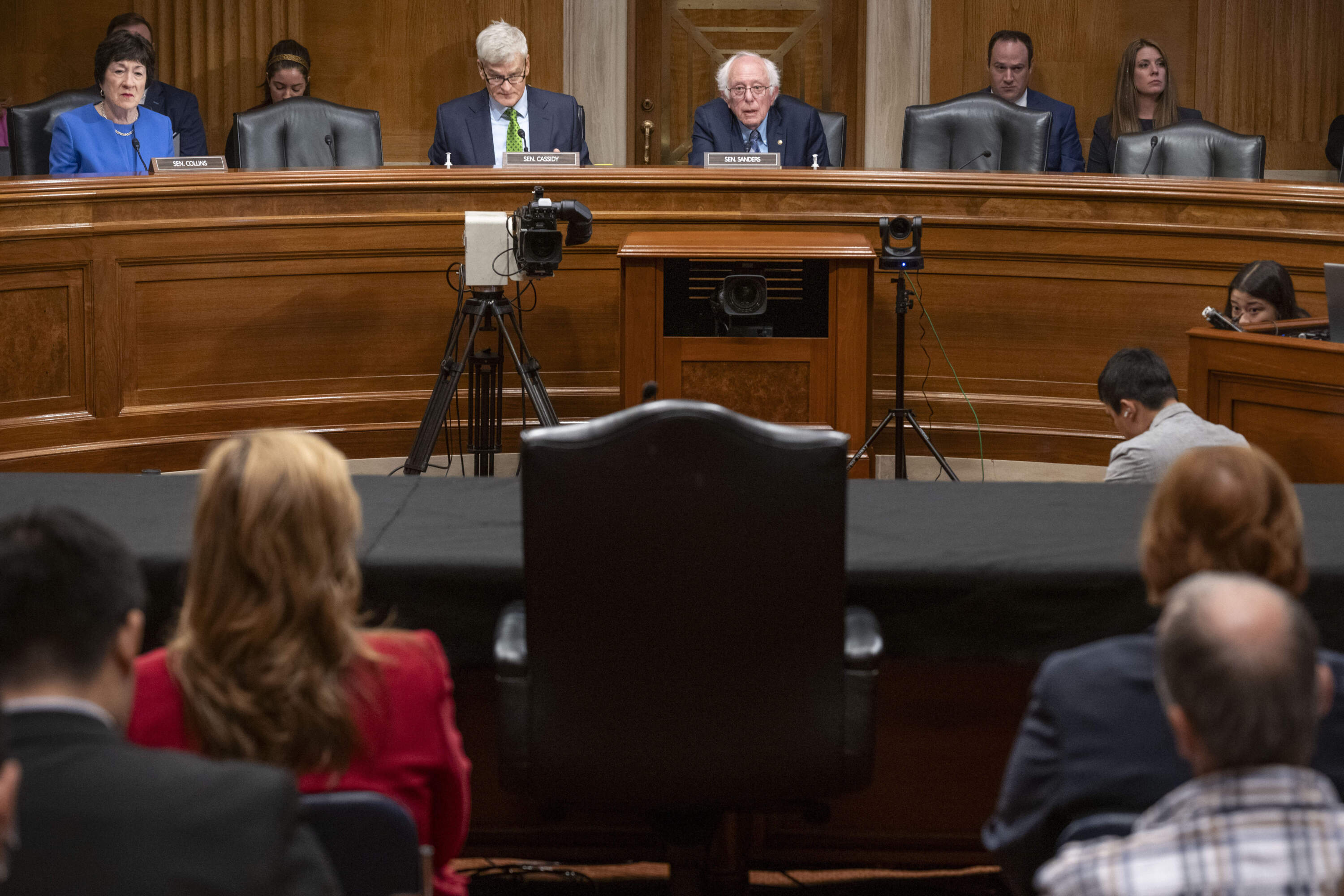 Sen. Bernie Sanders, I-Vt., top center, along with fellow Senators and staff look to the empty chair after Steward Health Care System CEO Ralph de la Torre failed to appear and testify at a Senate Health, Education, Labor, and Pensions hearing on Thursday, Sept. 12, 2024 on Capitol Hill in Washington. (AP Photo/Kevin Wolf)