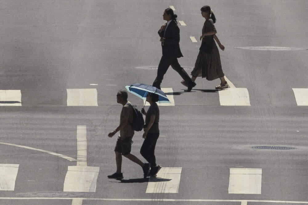 A pedestrian crosses a street holding an umbrella to protect herself from the sun in downtown Los Angeles during a heatwave Friday, Sept. 6, 2024, in Los Angeles. (AP Photo/Etienne Laurent)