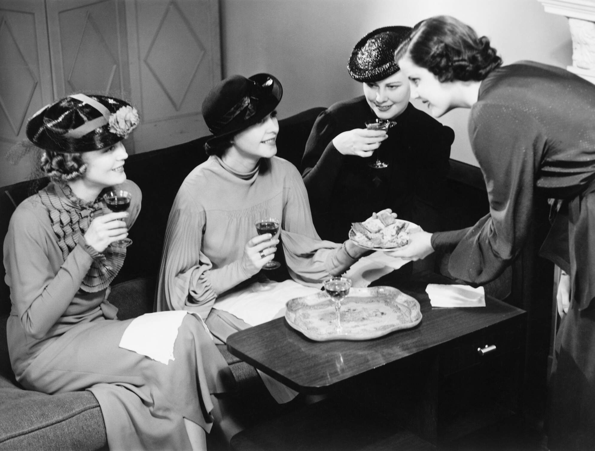 A group of women drinking wine and talking in a living room. (Getty Images)