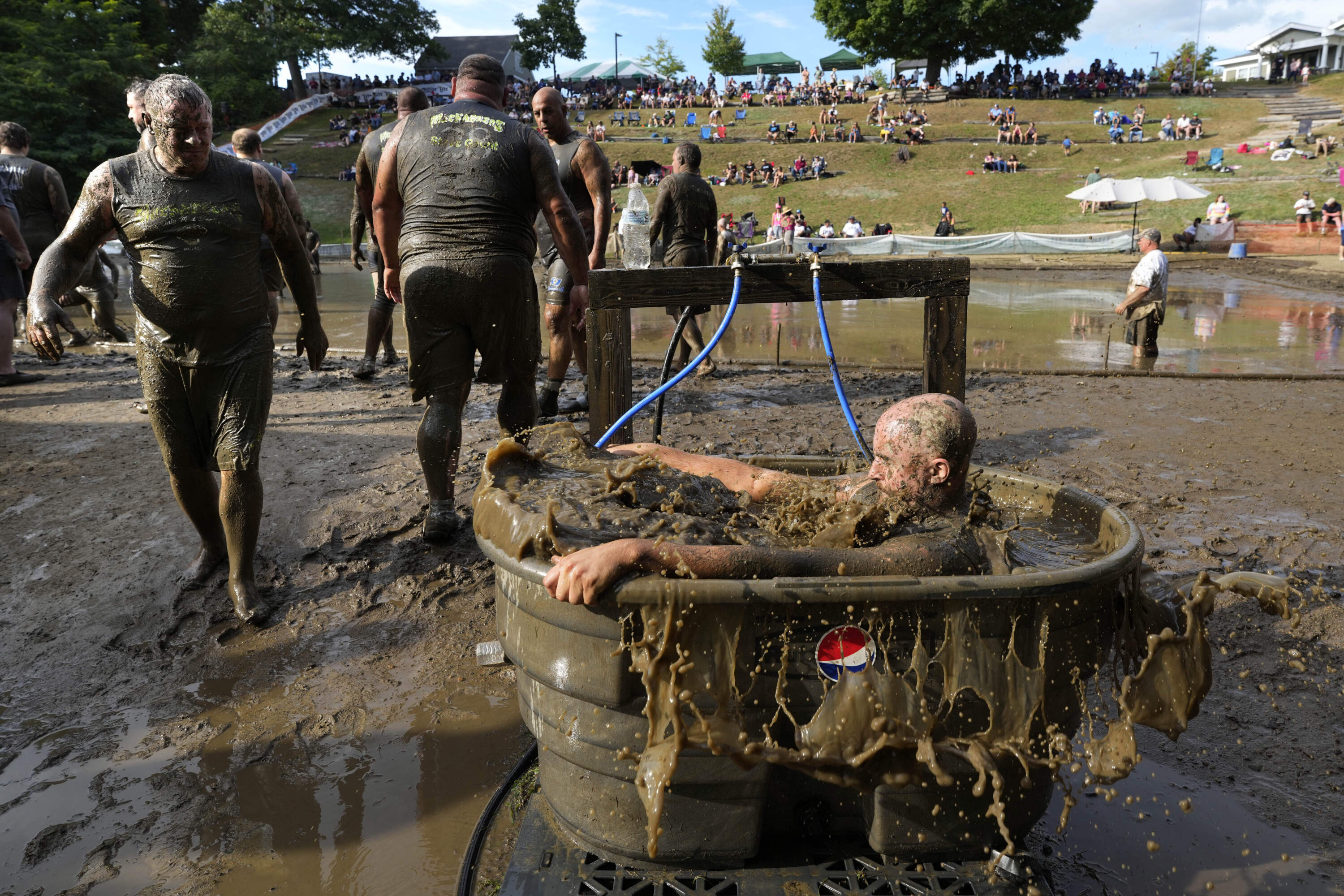 A Muckaneer's player dunks himself in a tub to clean off after a football game at the 2024 Mud Bowl. (Robert F. Bukaty/AP)