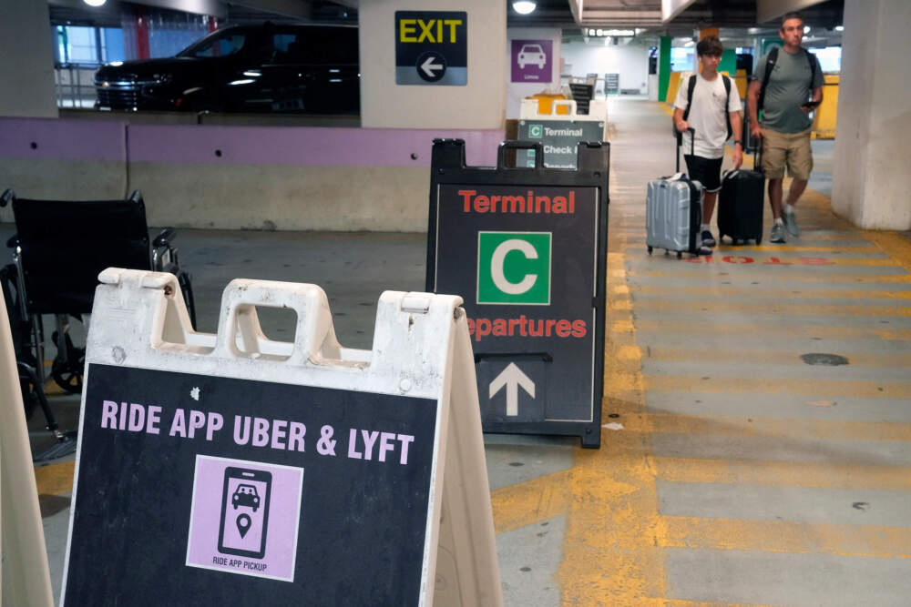 Travelers enter a pick up location for ride-hailing companies, including Uber and Lyft in the lower level of a parking garage at Logan International Airport in Boston. (Steven Senne/AP)