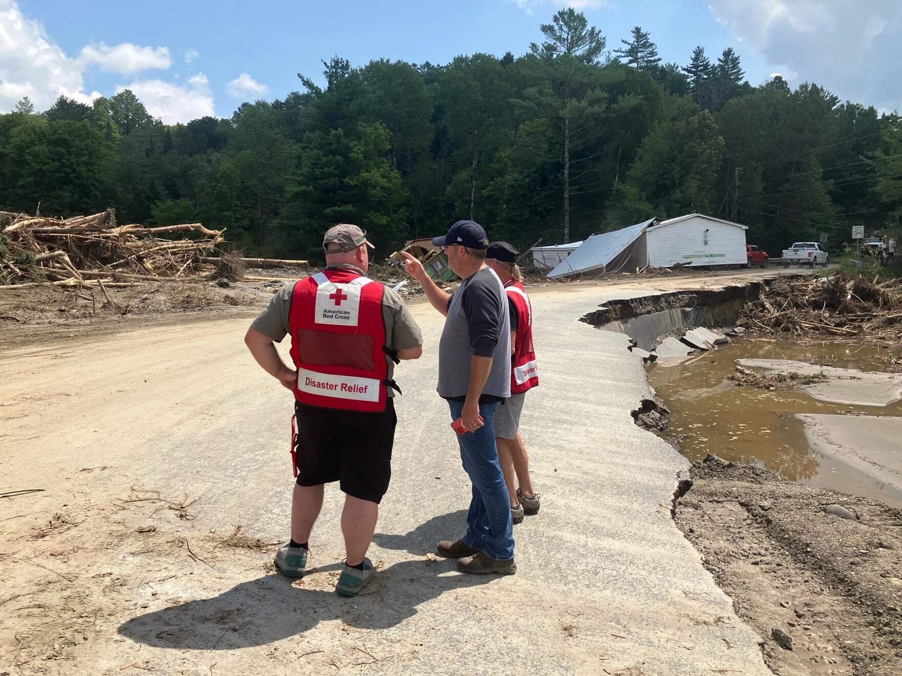 Lyndon Municipal Administrator Justin Smith, center, surveys flood damage in August with volunteers from the American Red Cross. (Peter Hirschfeld/Vermont Public)