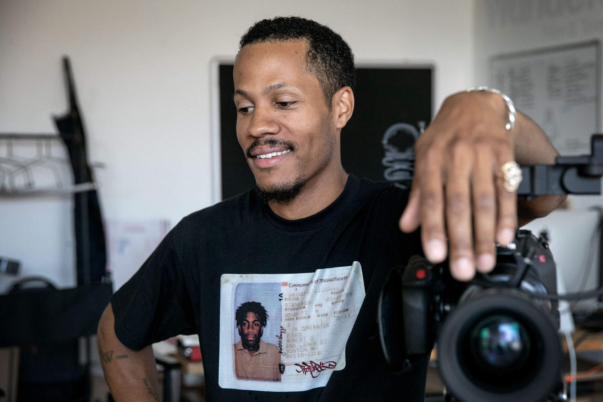 Filmmaker Mushen Kieta leans on a camera as he talks with a visitor at his studio in Boston. (Robin Lubbock/WBUR)