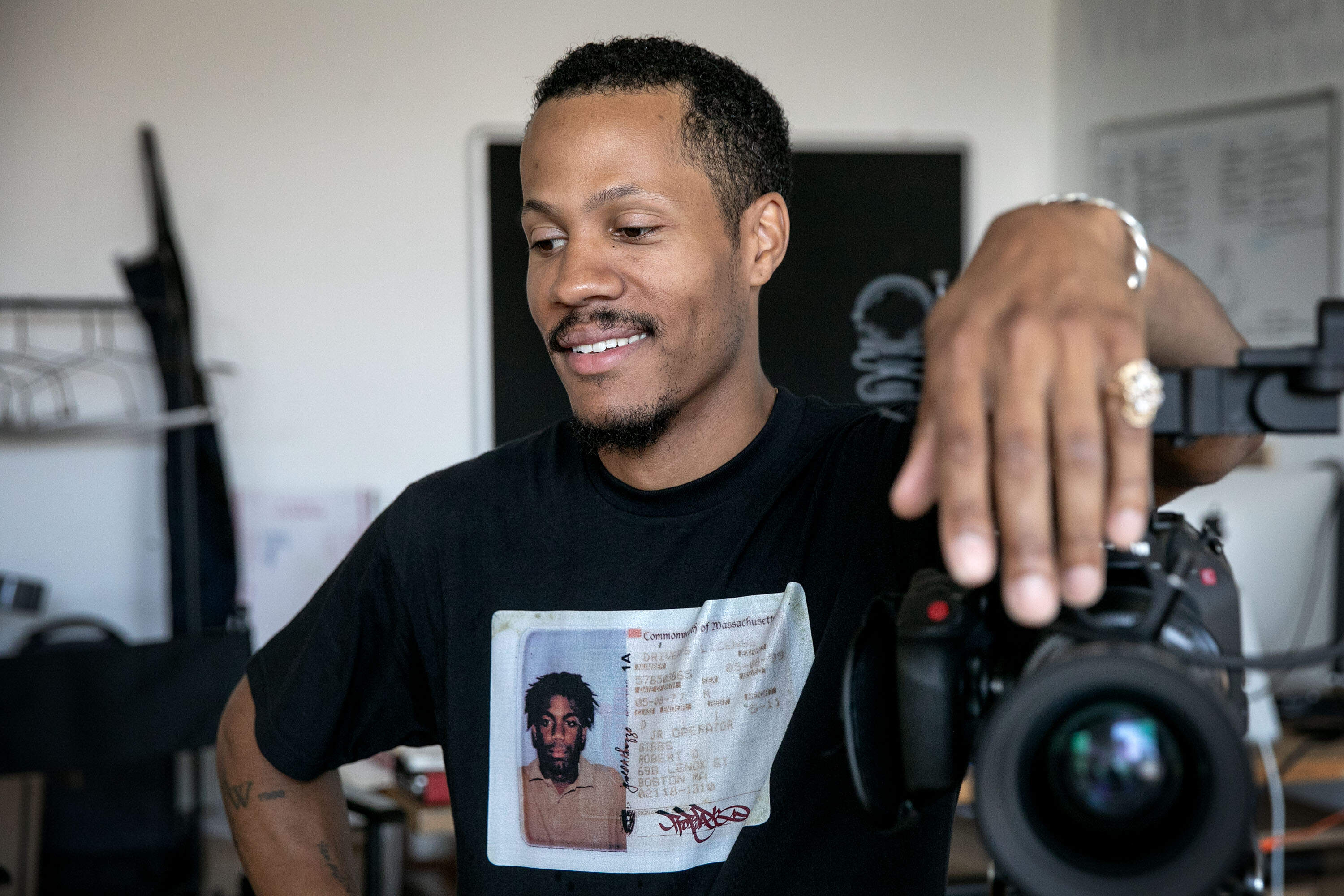 Filmmaker Mushen Kieta leans on a camera as he talks with a visitor at his studio in Boston. (Robin Lubbock/WBUR)