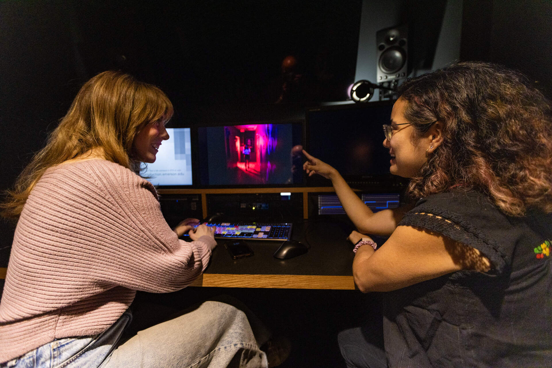 Filmmaker Maria Servellón (right) and editor Victoria Wojick color grade a scene from “Phantasma” in an editing room at Emerson College. (Jesse Costa/WBUR)