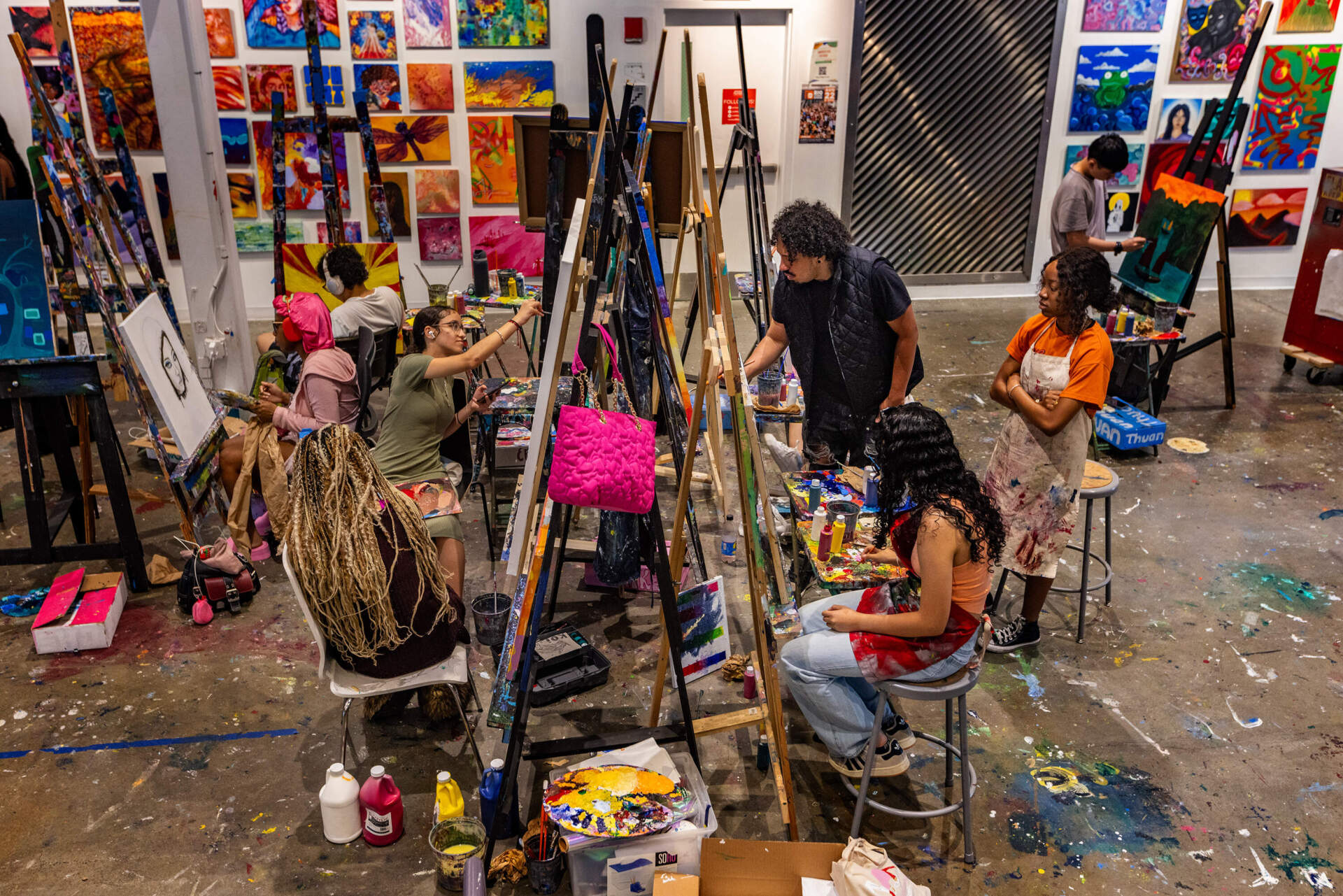 Jameel Radcliffe demonstrates a painting technique to student Arike Akinbolagbe during a class at Artists For Humanity. (Jesse Costa/WBUR)