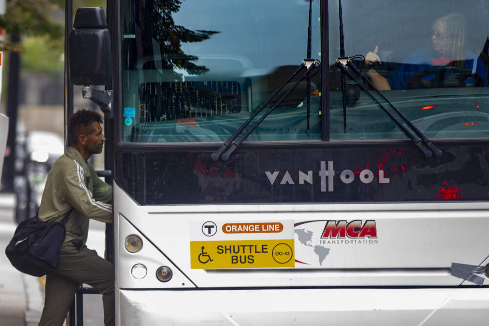 A bus driver on an MBTA Orange Line shuttle bus gestures to a commuter. (Jesse Costa/WBUR)