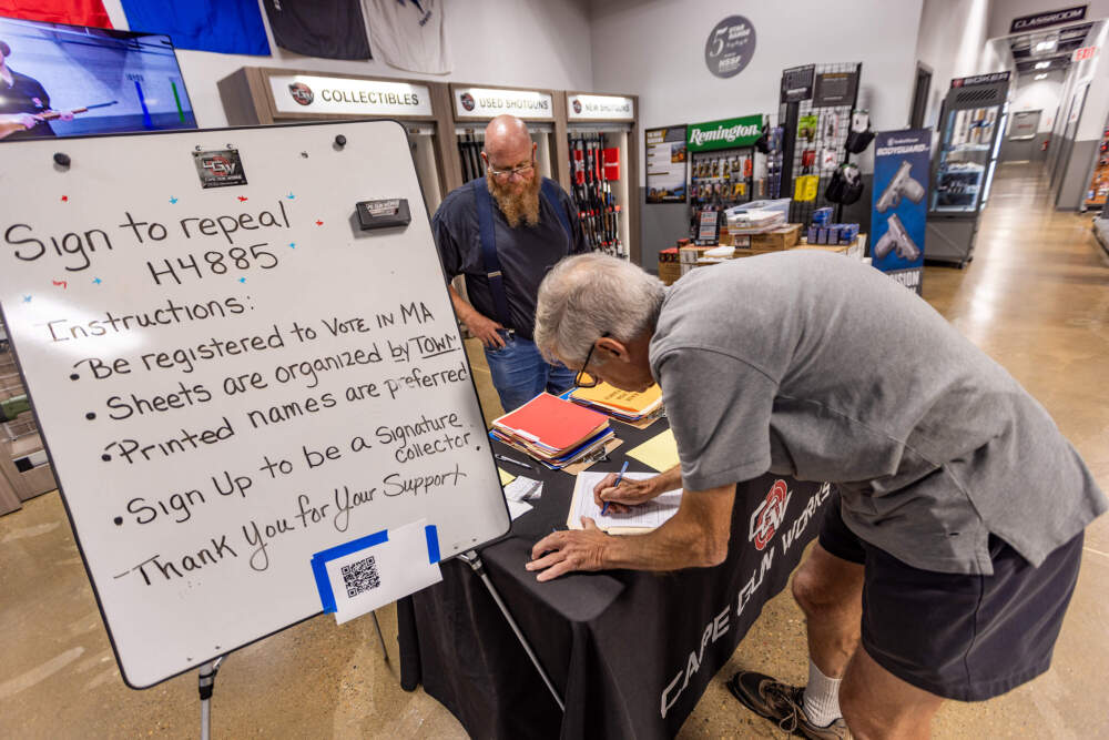 John Mawhinney, a civil rights coalition state field coordinator, watches as Martin Laspada of Bourne signs a petition to repeal the state's new gun reform law. (Jesse Costa/WBUR)