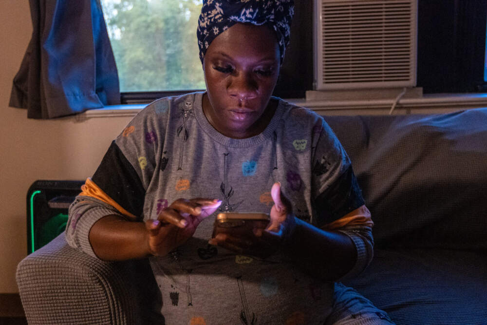 Kiki Polk checks her electric bill on her phone to see if the credit has been applied to her account from the Boston Medical Center Clean Power Prescription program. (Jesse Costa/WBUR)