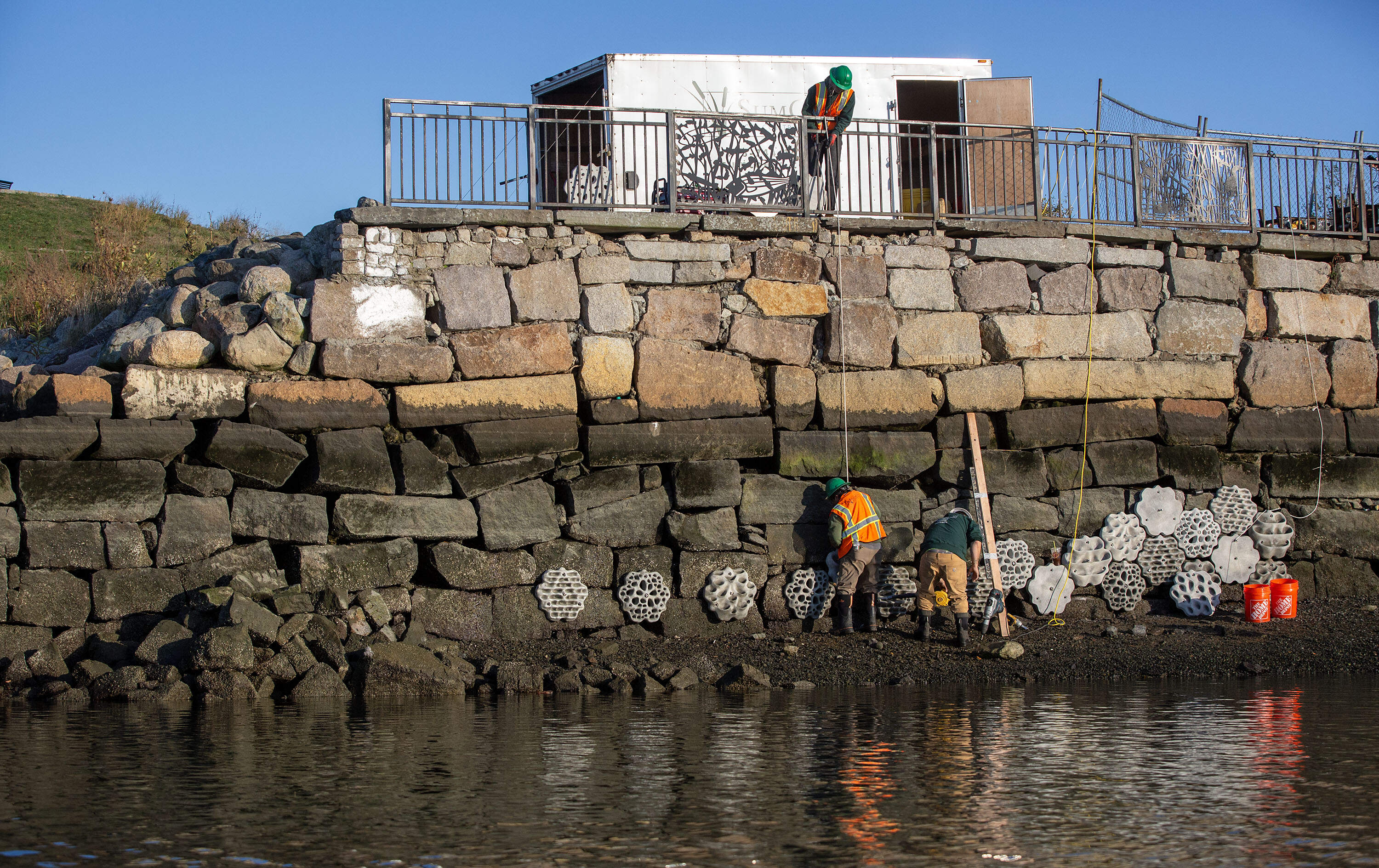 SumCo Eco-Contracting staff fix panels into the new living seawall at the Condor Street Urban Wild in East Boston. (Robin Lubbock/WBUR)