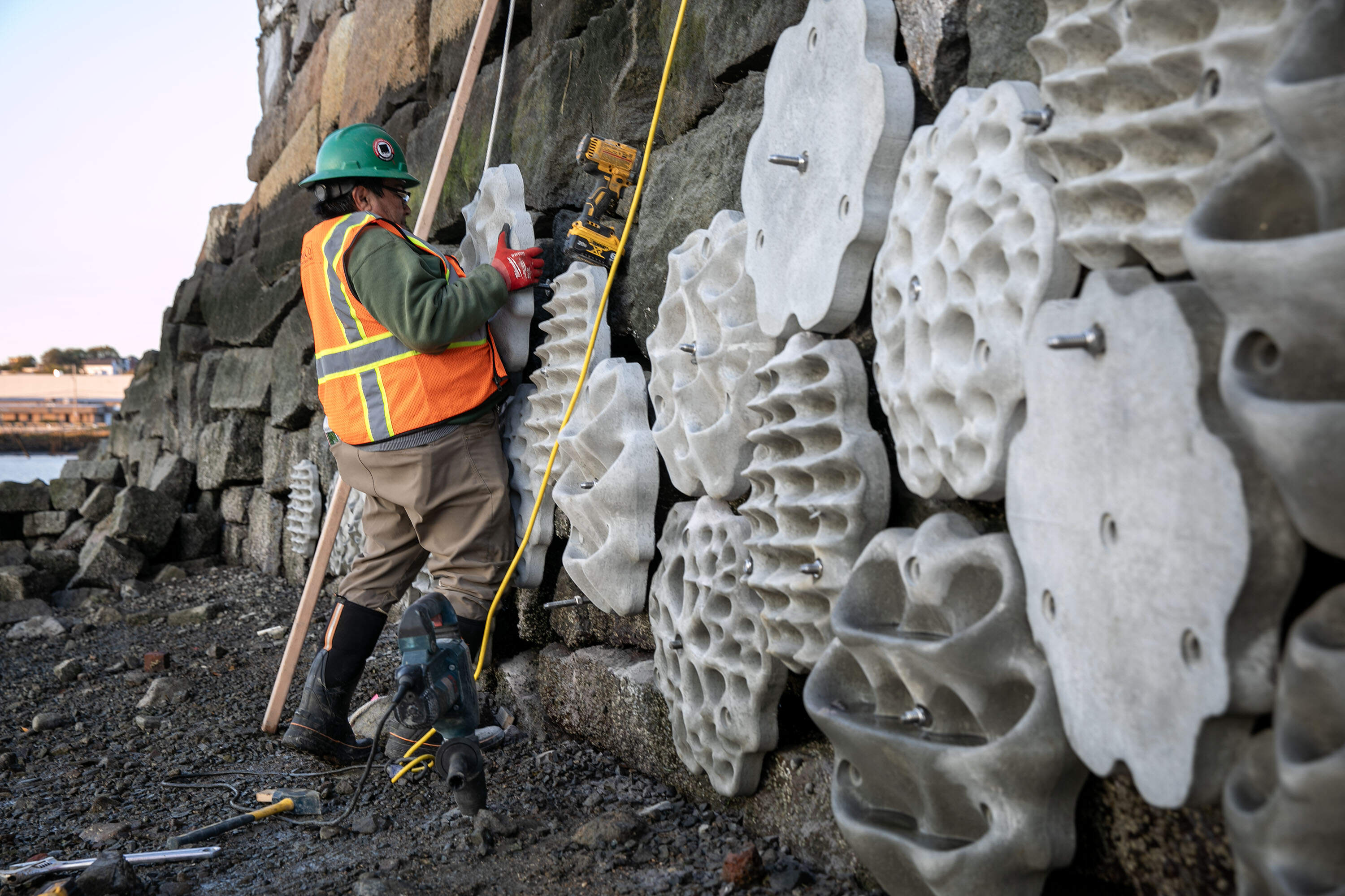 Hugo Urbina, of SumCo Eco-Contracting, lifts a panel into the new living seawall at the Condor Street Urban Wild in East Boston. (Robin Lubbock/WBUR)