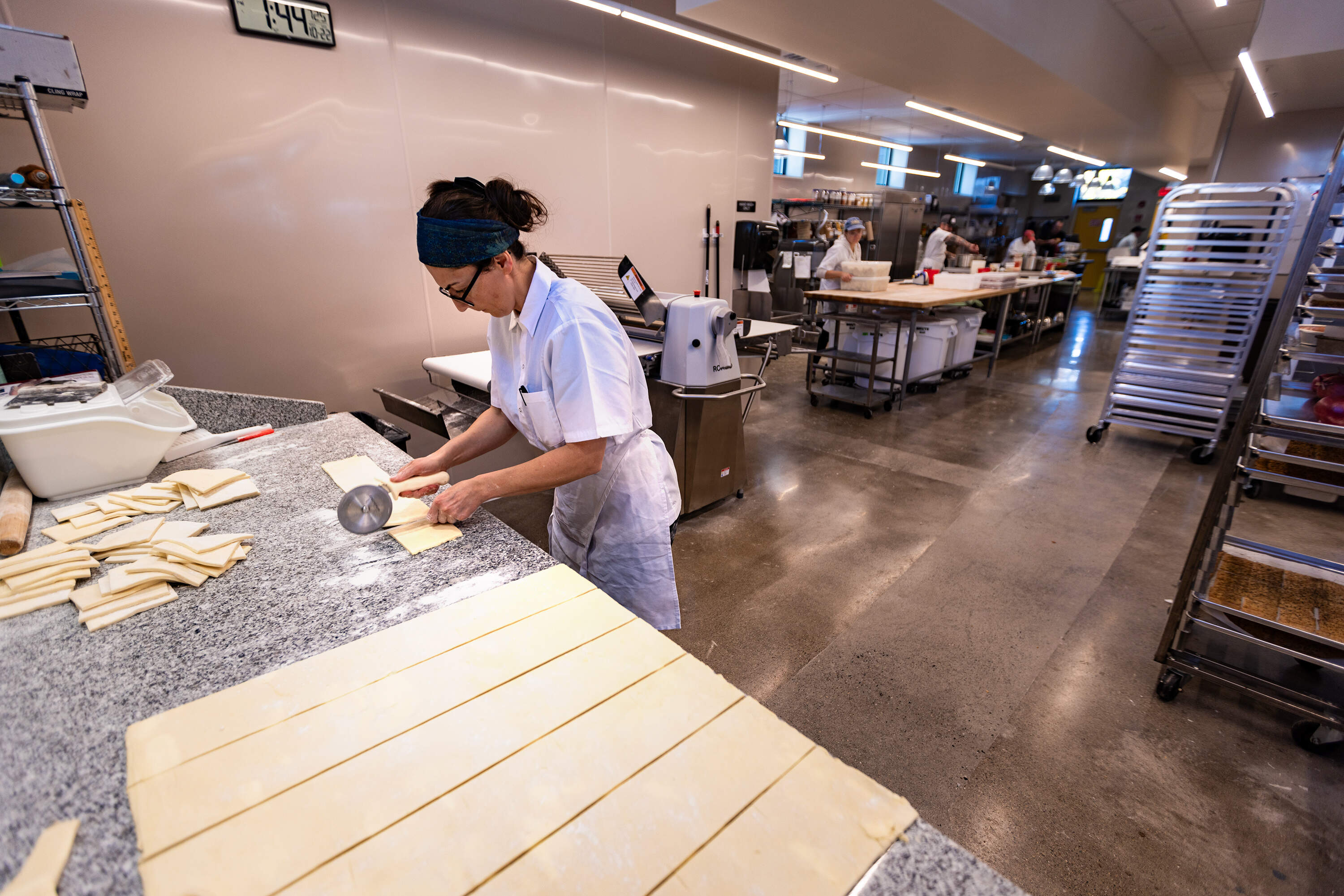 Sofra Pastry chef Feyza Özden cuts cake dough for the next day's turnover in the newly expanded kitchen space in Allston. (Jesse Costa/WBUR)