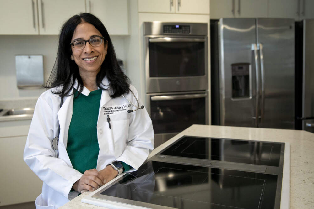 Dr. Yamini Levitzky, who leads the South Asian Heart Health and Nutrition Program at Newton-Wellesley Hospital, stands by a cooktop in the culinary medicine kitchen at her office in Newton. (Robin Lubbock/WBUR)