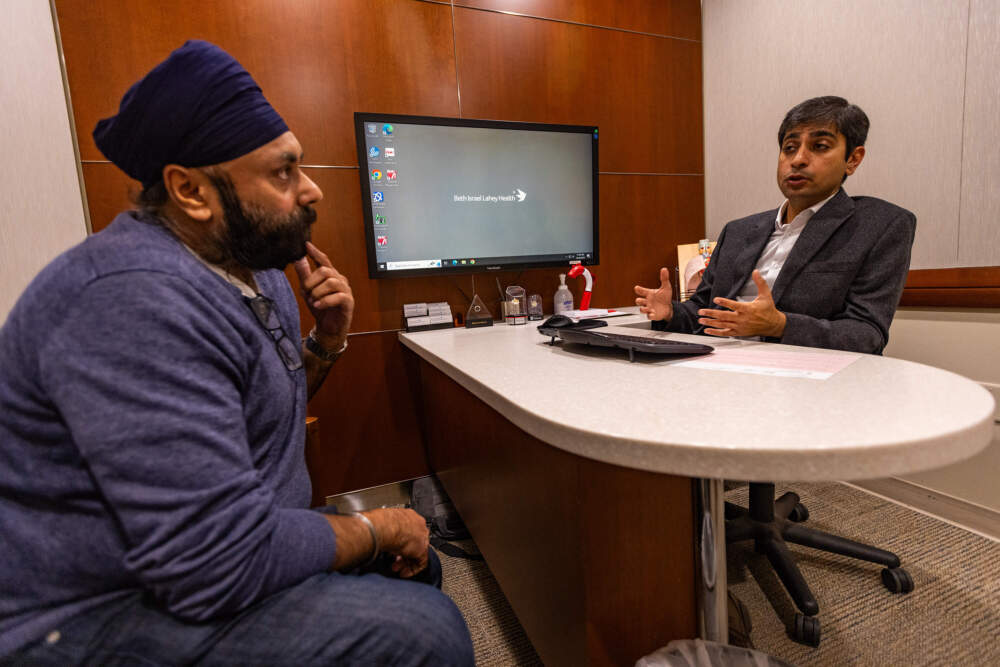 Dr. Sarju Ganatra consults with his patient Pushpir Bhetia during an appointment at Lahey Hospital and Medical Center in Burlington. (Jesse Costa/WBUR)