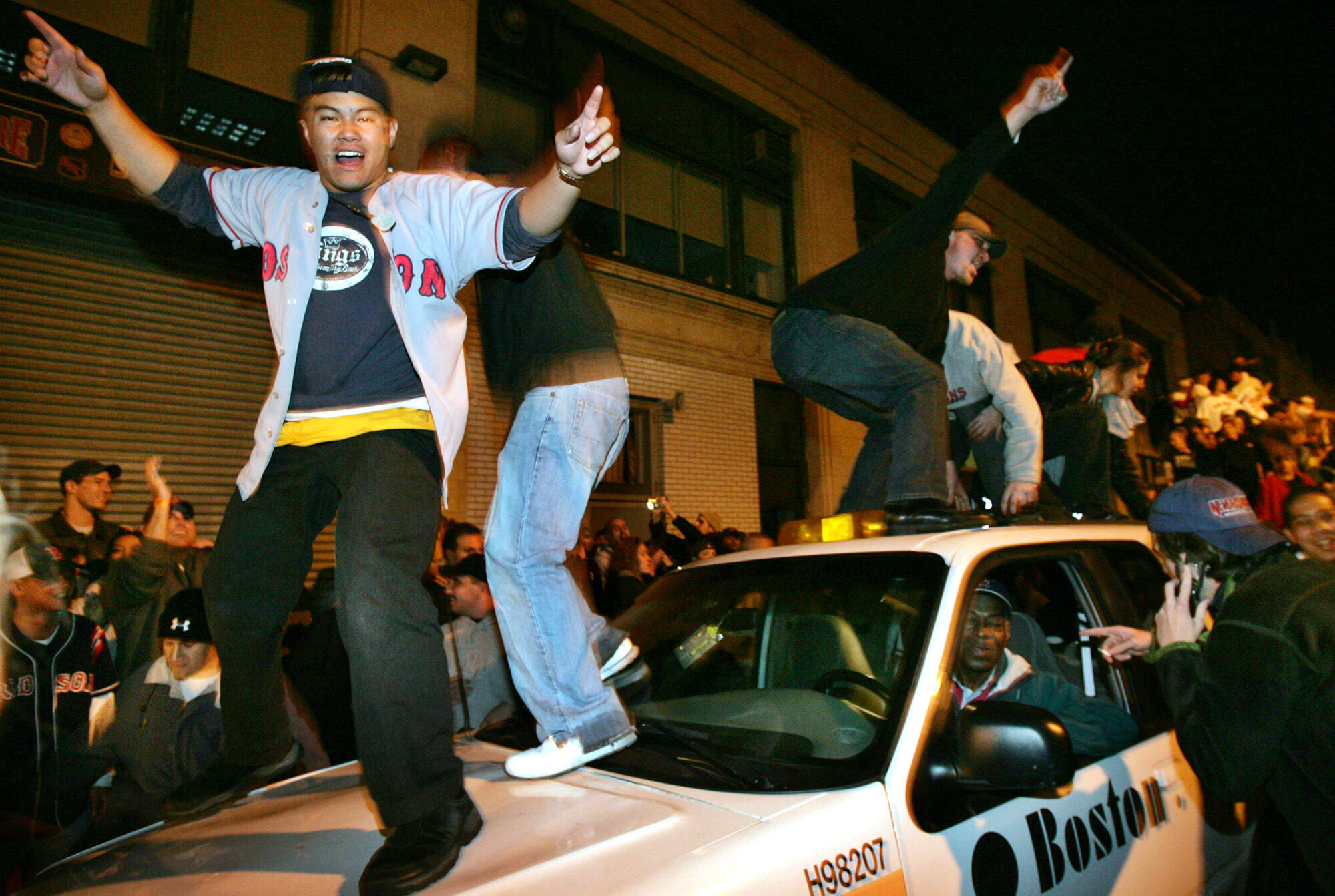 Boston Red Sox fans dance on a car as they celebrate outside Boston's Fenway Park moments after the Red Sox beat the New York Yankees in the American League playoffs on Oct. 20, 2004. (Steven Senne/AP)