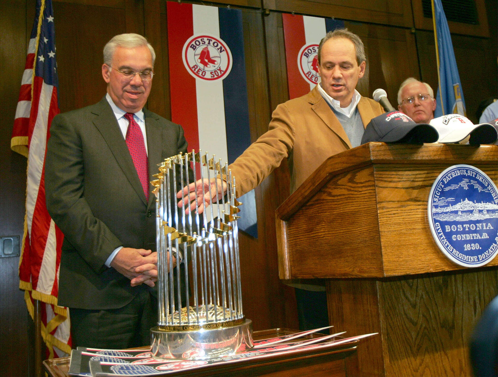 Boston Re Sox President/CEO Larry Lucchino, center, shows the World Series trophy during a news conference at the City Hall in Boston, Thursday, Oct. 28, 2004, as Boston Mayor Thomas Menino, left, and Boston Police Deputy Superintendent Robert Dunford, right, look on. (Chitose Suzuki/AP)