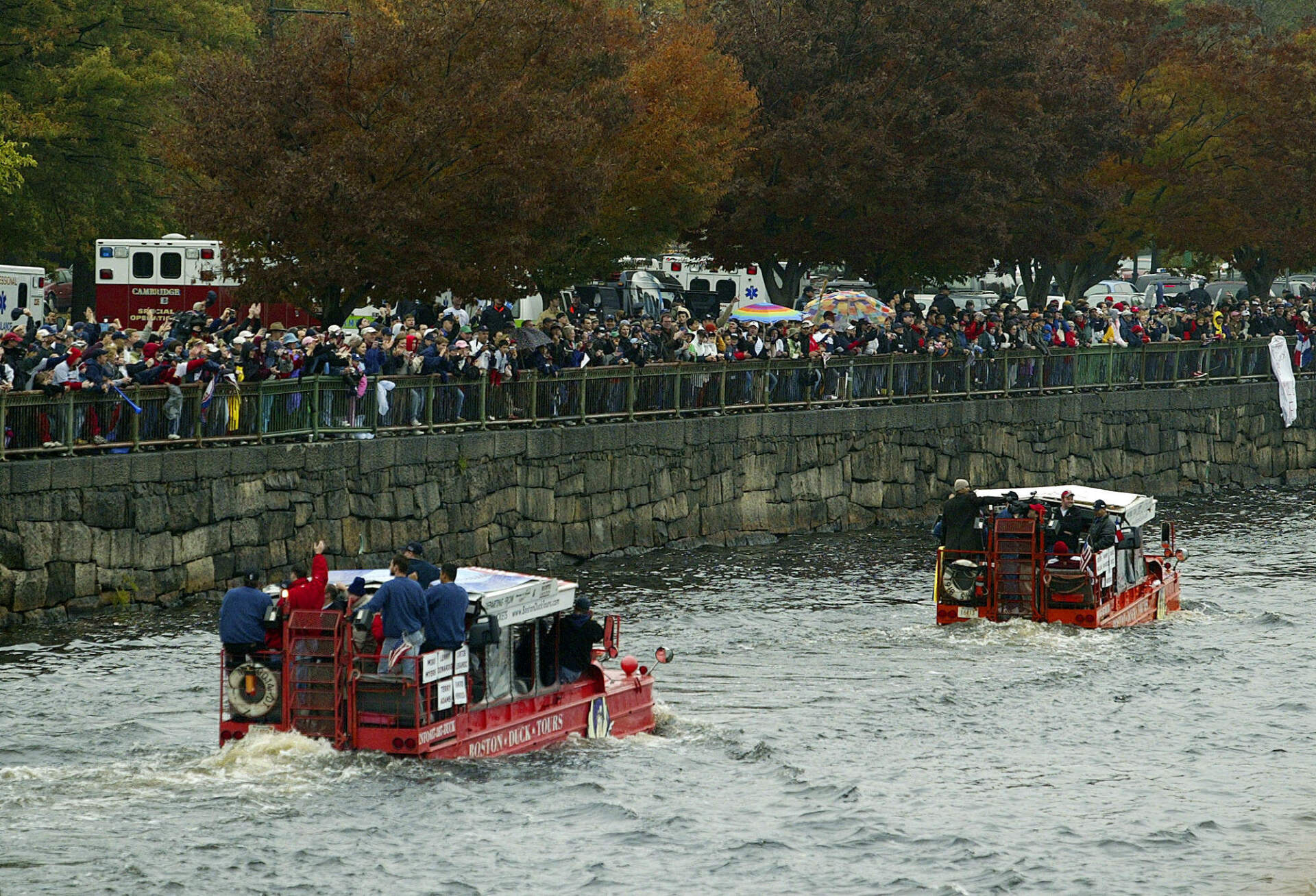 Boston Red Sox fans line the banks of the Charles River as the Boston Red Sox parade down the river in duck in Boston, Saturday, Oct 30, 2004. (Julia Malakie/AP)