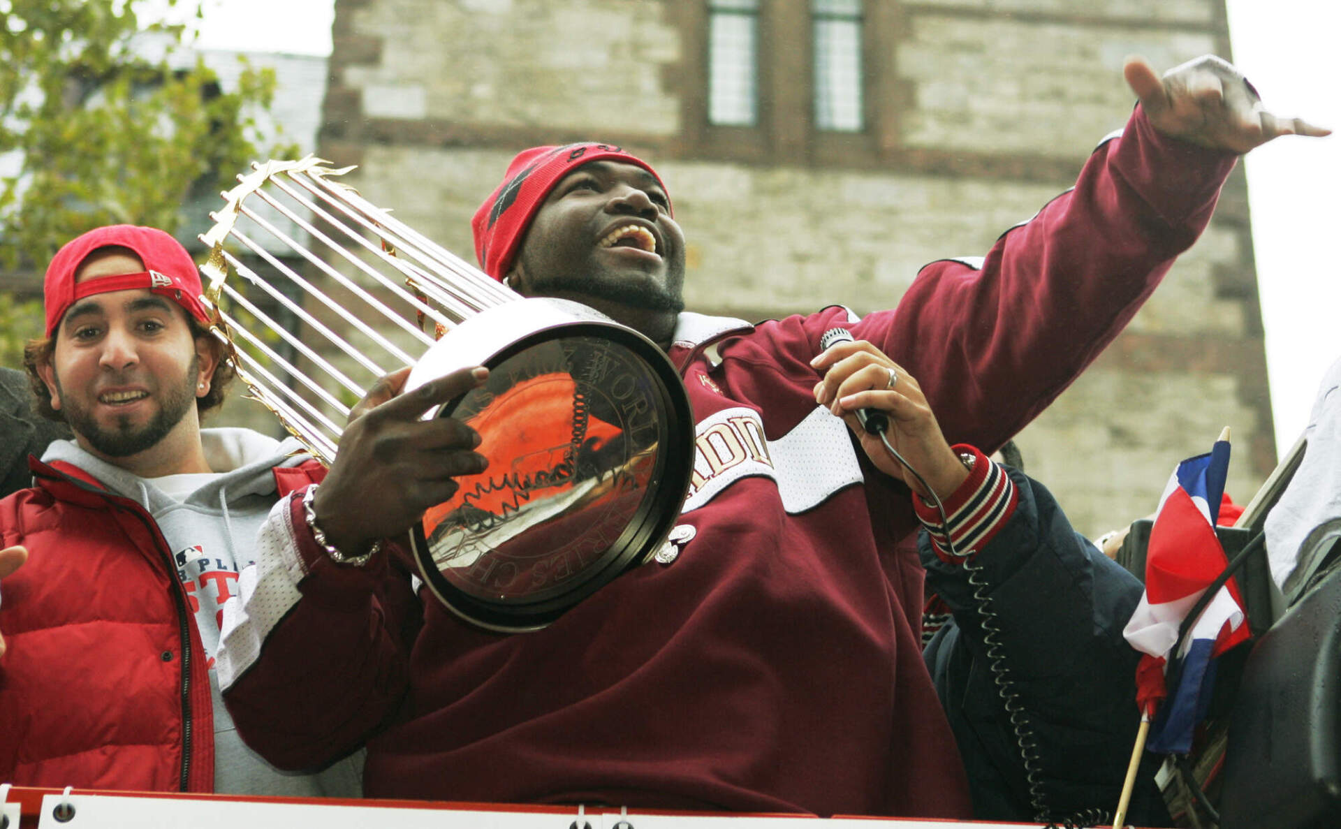 Boston Red Sox star David Ortiz smiles and waves to cheering fans as he holds the World Series trophy during the rolling rally in Boston, Saturday, Oct. 30, 2004, to celebrate the Red Sox World Series victory. (Elise Amendola/AP)