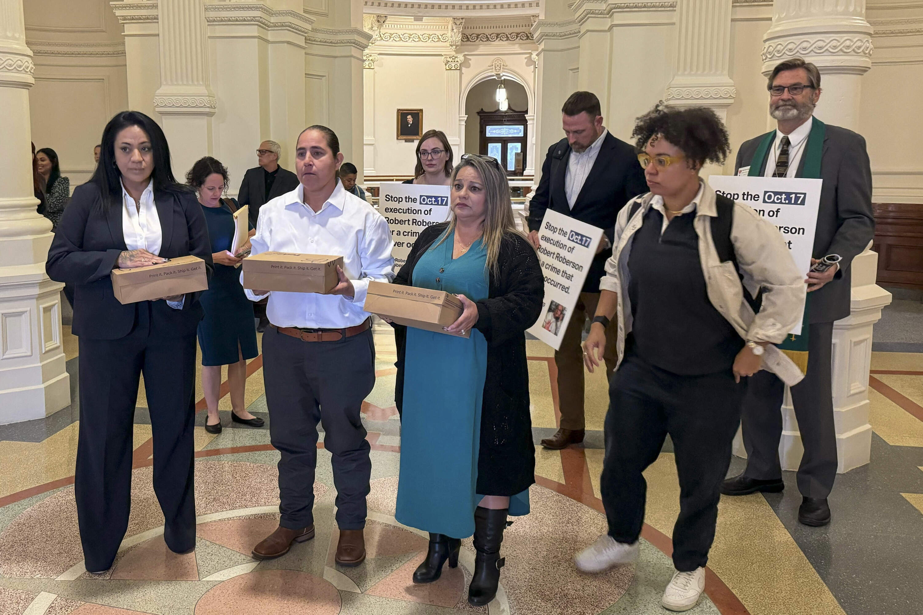 Casandra Rivera, left, Anna Vasquez, second from left, and Elizabeth Ramirez, center, of the "San Antonio 4" group, hold boxes with petitions being delivered in the Texas State capitol for Texas Gov. Greg Abbott seeking the pardoning of Robert Roberson's execution. (Nadia Lathan/AP)