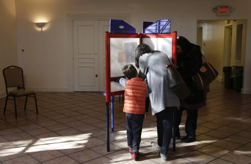A woman marks her votes on a ballot as a child looks on. (Julie Jacobson/AP)