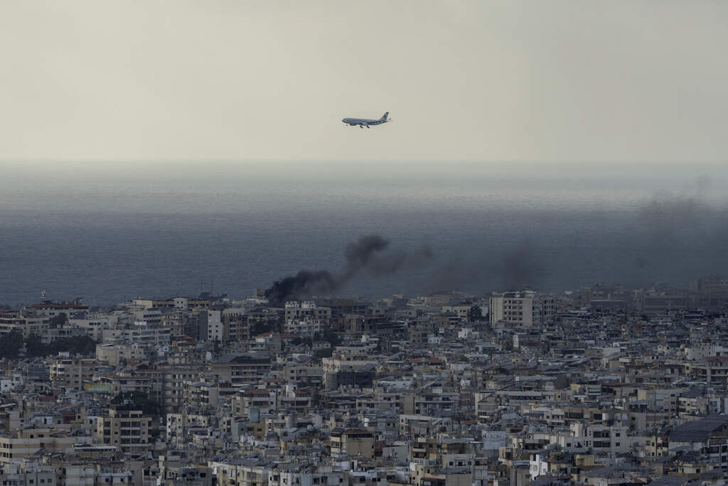 A Middle East Airlines airplane flies over Beirut as smoke rises from Dahiyeh, in Beirut, Lebanon, Tuesday, Oct. 1, 2024. (AP Photo/Bilal Hussein)