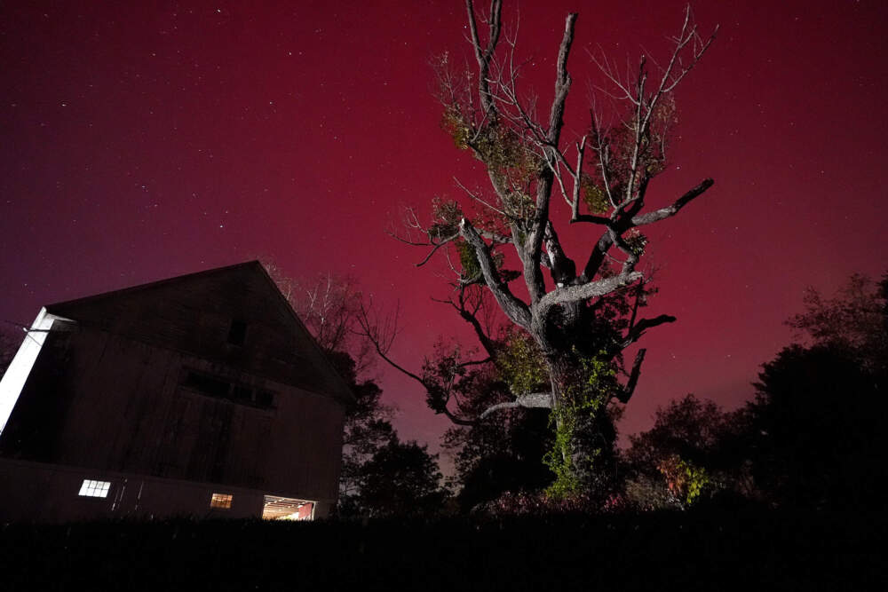 An aurora borealis glows red in the sky above a barn in East Derry, NH, Oct. 10, 2024. (Charles Krupa/AP)