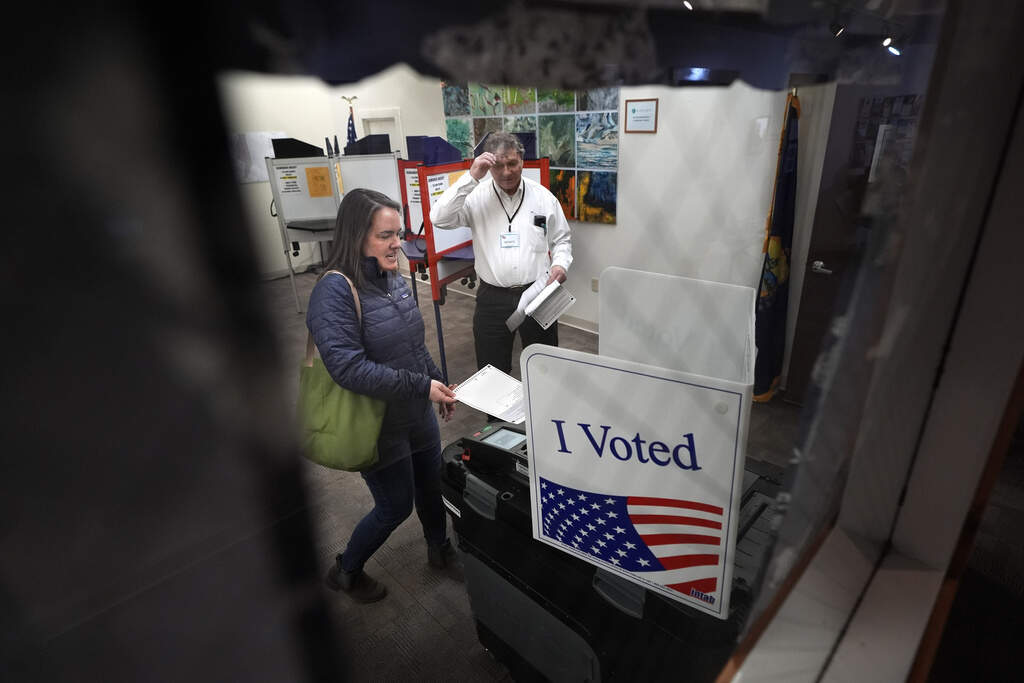 Amber Cutler casts her ballot as election official Monte Mason looks on during primary election voting March 5, 2024, at the town hall in Morrisville, Vt. (AP Photo/Robert F. Bukaty, File)