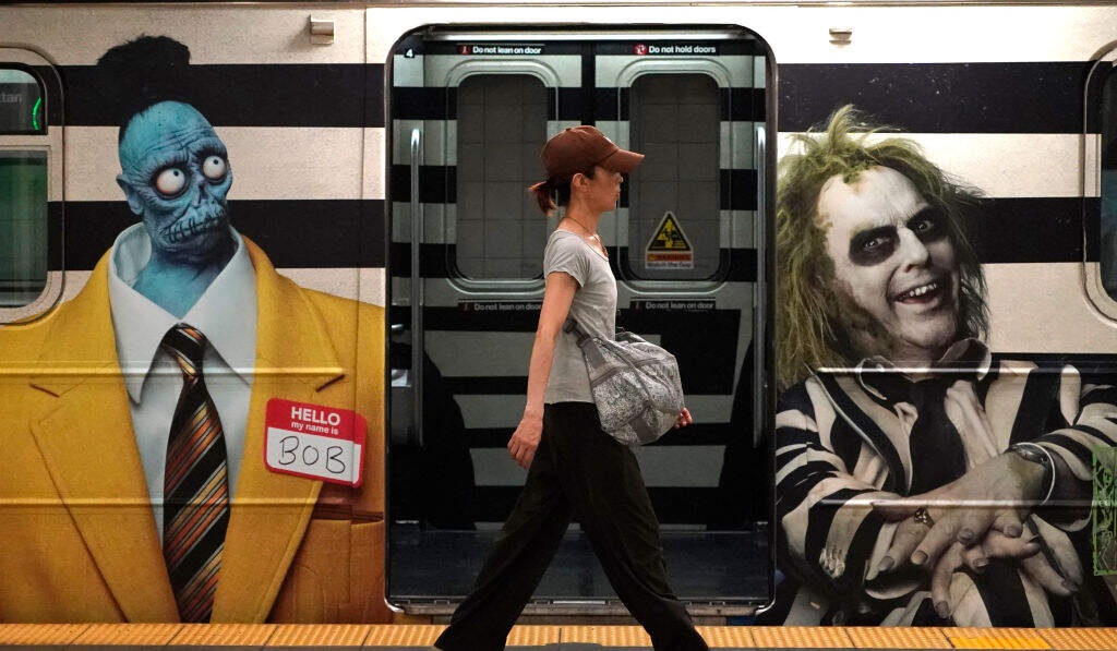 A person walks past advertisements for Tim Burton's upcoming film, "Beetlejuice Beetlejuice", wrapped on the New York subway 42nd street shuttle, August 15, 2024. (Photo by TIMOTHY A. CLARY/AFP via Getty Images)