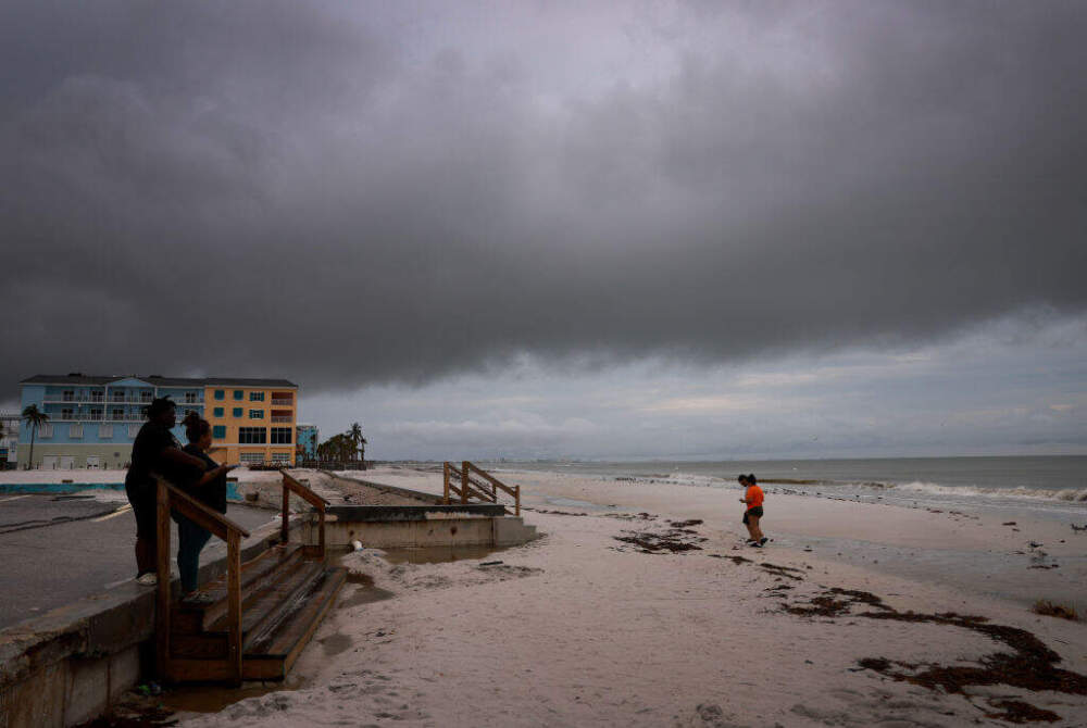 People visit the beach Tuesday in Fort Myers, Florida as storm clouds hang overhead before Hurricane Milton's arrival. (Joe Raedle/Getty Images)