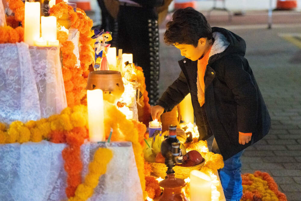 A boy lights a candle on an ofrenda at Chelsea's Dia de los Muertos celebration. (Photo courtesy of the City of Chelsea)
