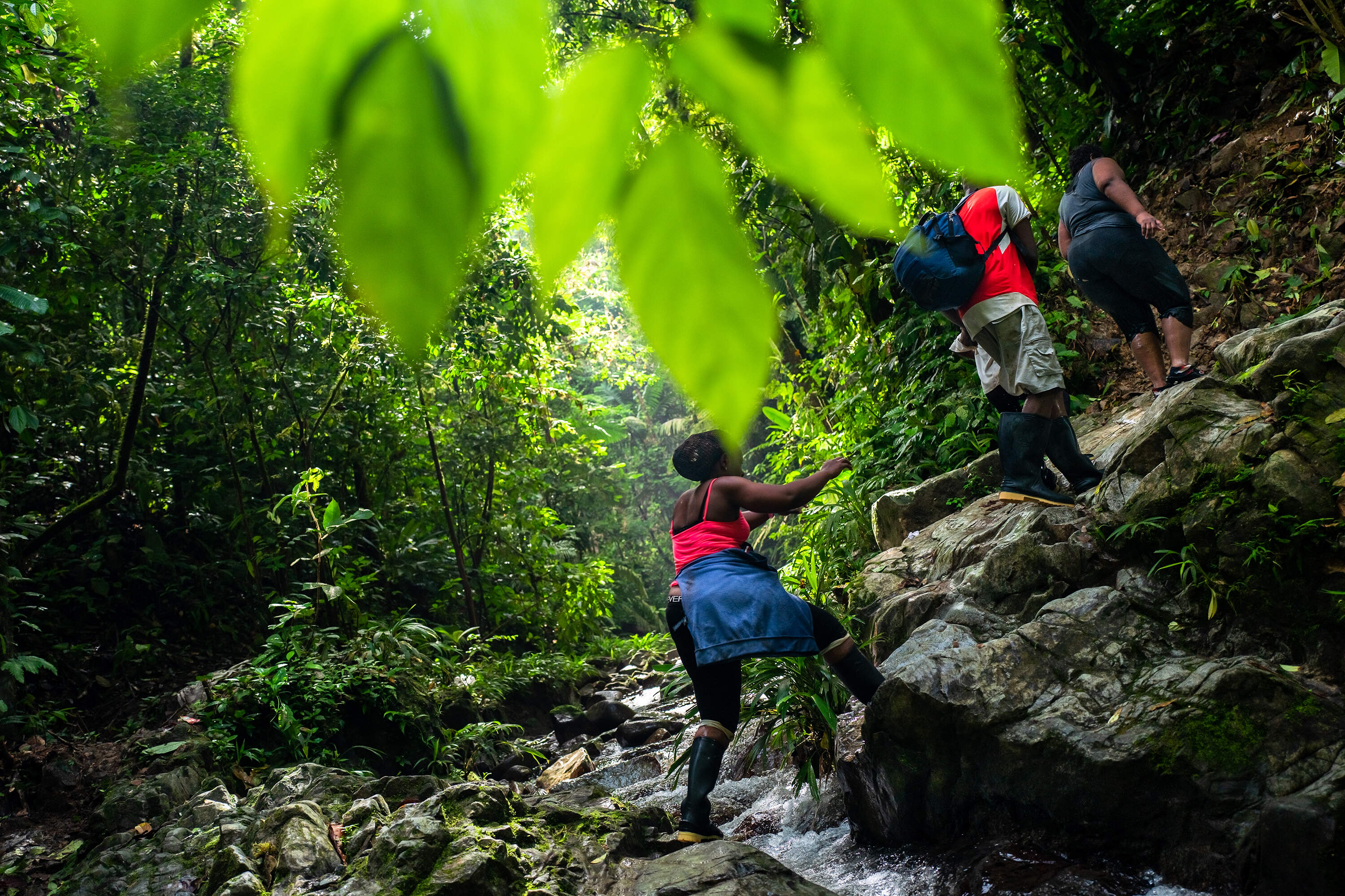 Migrants from Haiti cross a stream while climbing a rocky trail in the wild and dangerous jungle in the portion of the Darién Gap within Colombia in 2022. (Jan Sochor/Getty Images)