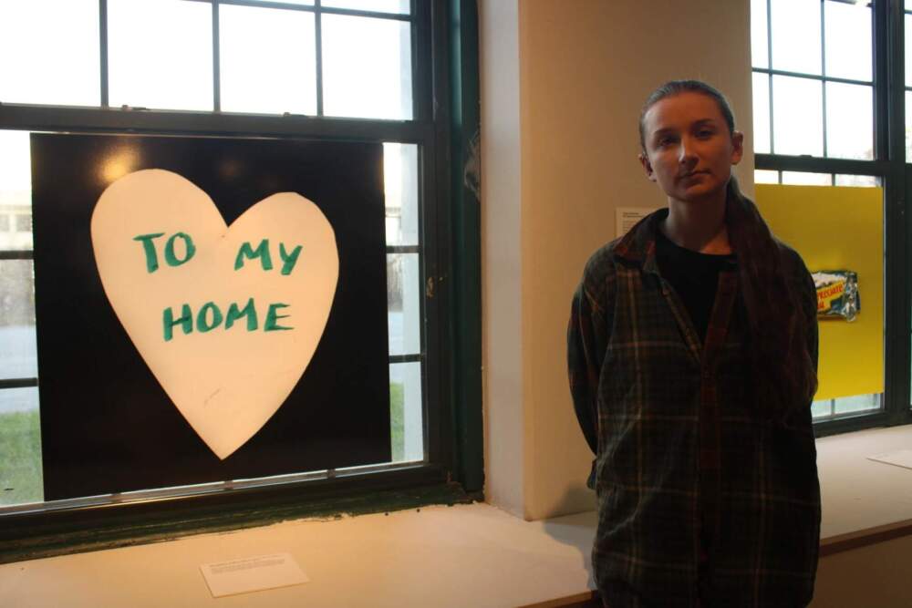 Lewiston artist and teacher Mia Zellner at a mill in Maine on October 22, 2024. Immediately after the shooting, Zellner made dozens of heart-shaped signs like the one pictured and posted them throughout the city. They collaborated with Hollander to install the bouquet sleeve. (Ari Snyder/Maine Public)