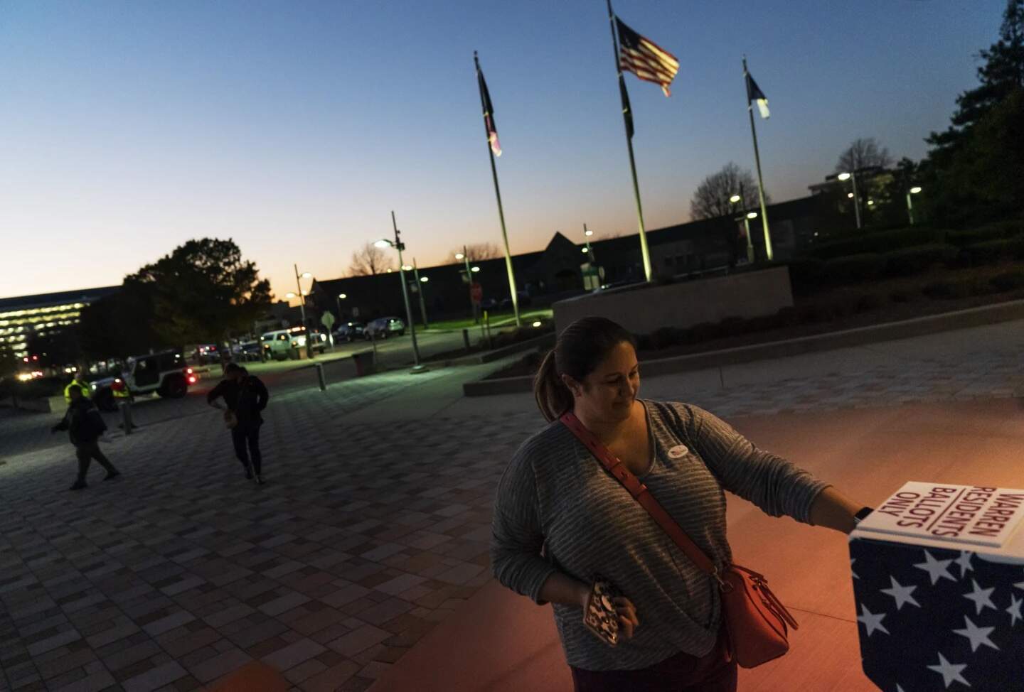 Wendy Gill inserts her absentee ballot at a drop-off box as the sun sets on Election Day outside City Hall in Warren, Mich., Nov. 3, 2020. (David Goldman/AP)