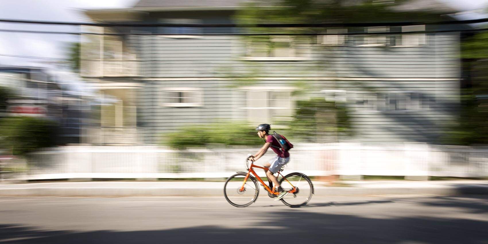 A cyclist rides a bicycle through Cambridge, Mass. on a summer morning. (Robin Lubbock/WBUR)