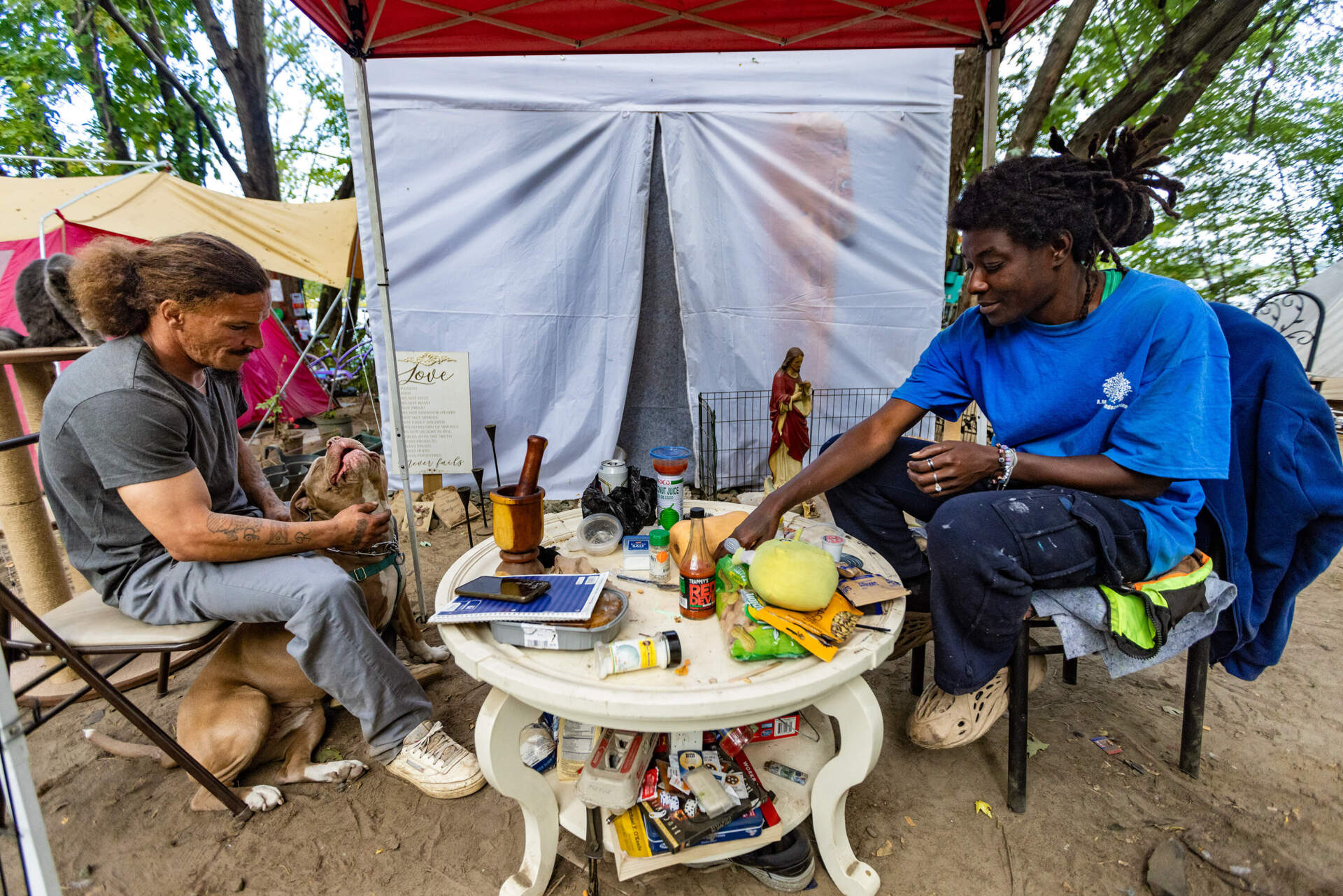 Francisco and Neva sit in front of their tent in a Lowell encampment before Francisco goes to his job as a landscaper. Neva says it's the first place they've felt a little bit stable for years. (Jesse Costa/WBUR)