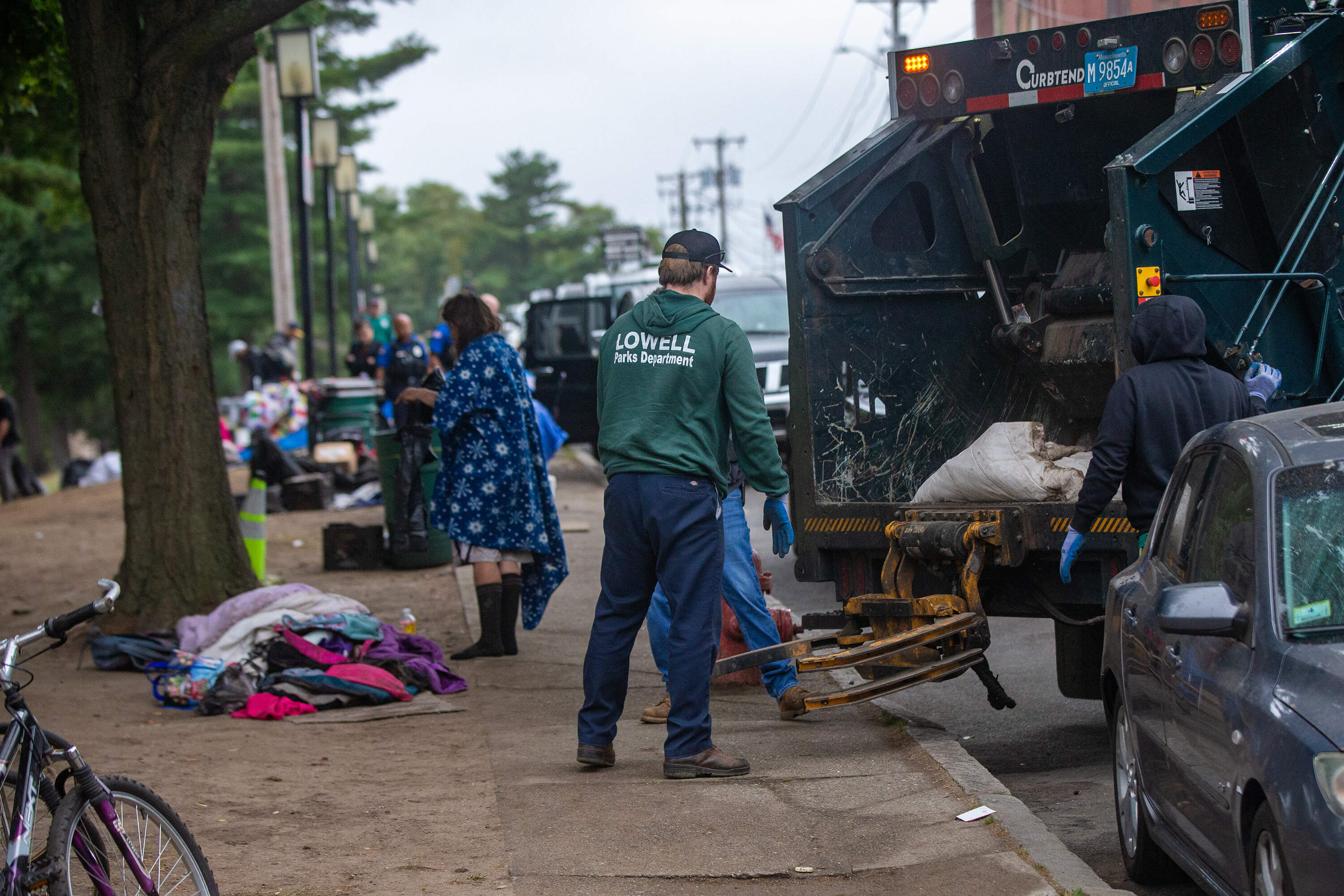 Lowell Parks Department workers remove items from a homeless encampment on South Common. (Jesse Costa/WBUR)